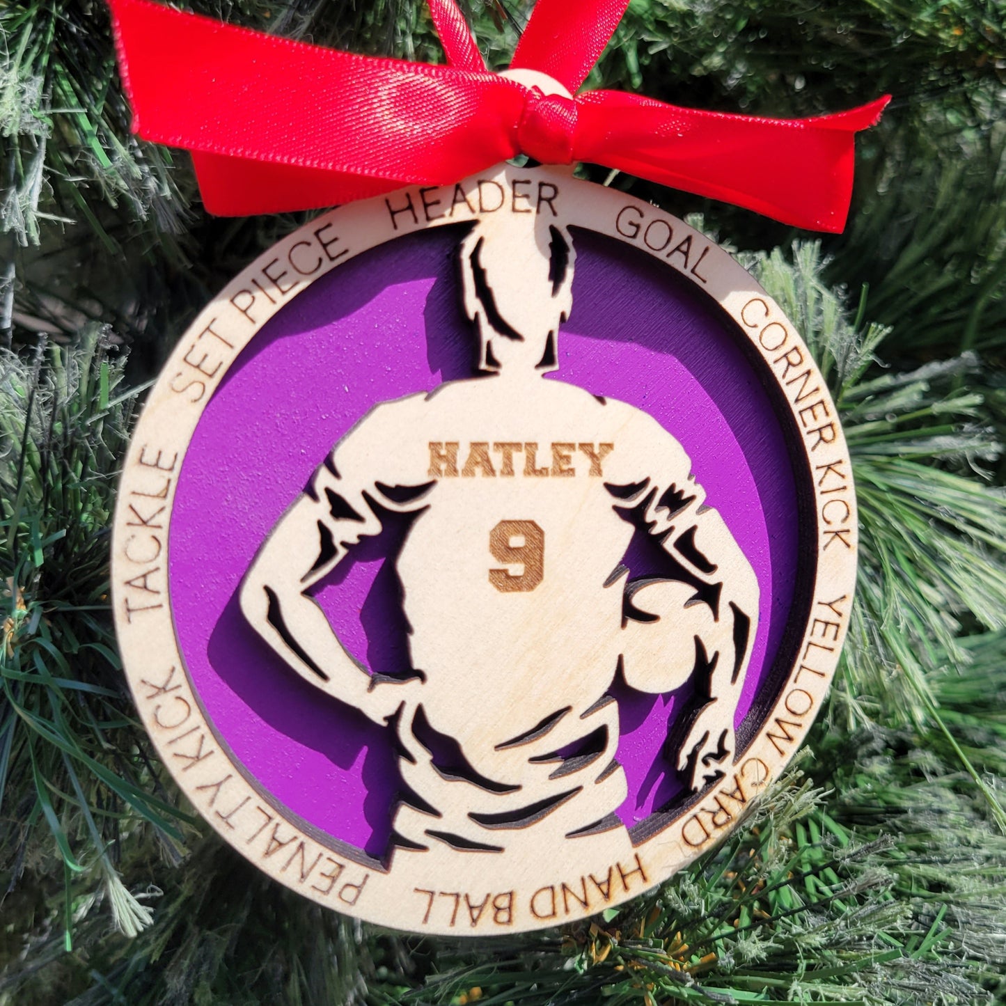 Decorative sports-themed ornament with a red ribbon on a Christmas tree. soccer player christmas gift, christmas ornament for soccer player, personalized soccer player christmas ornament