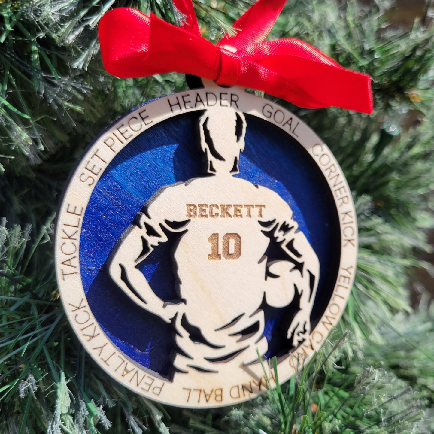 Decorative sports-themed ornament with a red ribbon on a Christmas tree. soccer player christmas gift, christmas ornament for soccer player, personalized soccer player christmas ornament