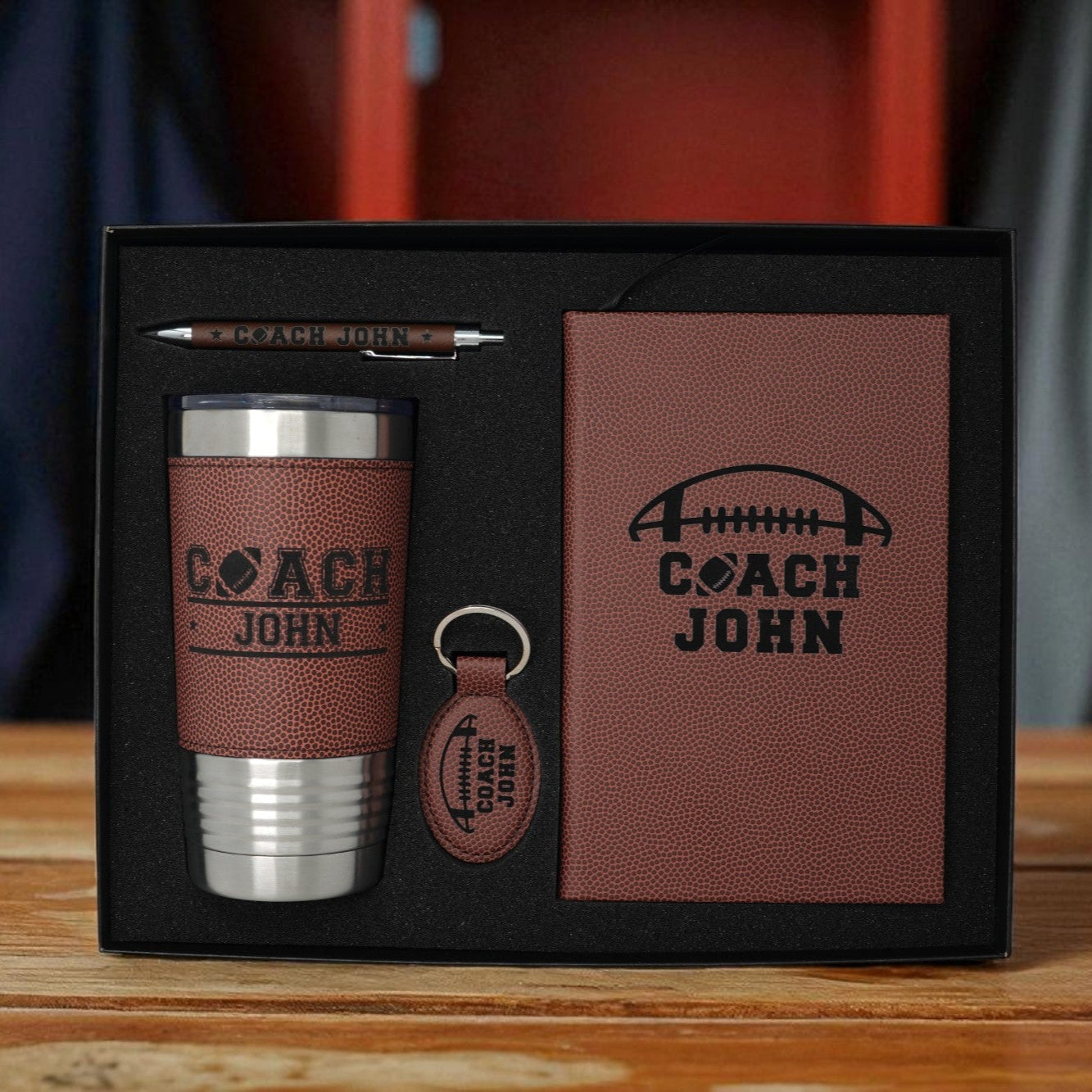 Gift set with tumbler, keychain, and card in a box on a wooden surface.