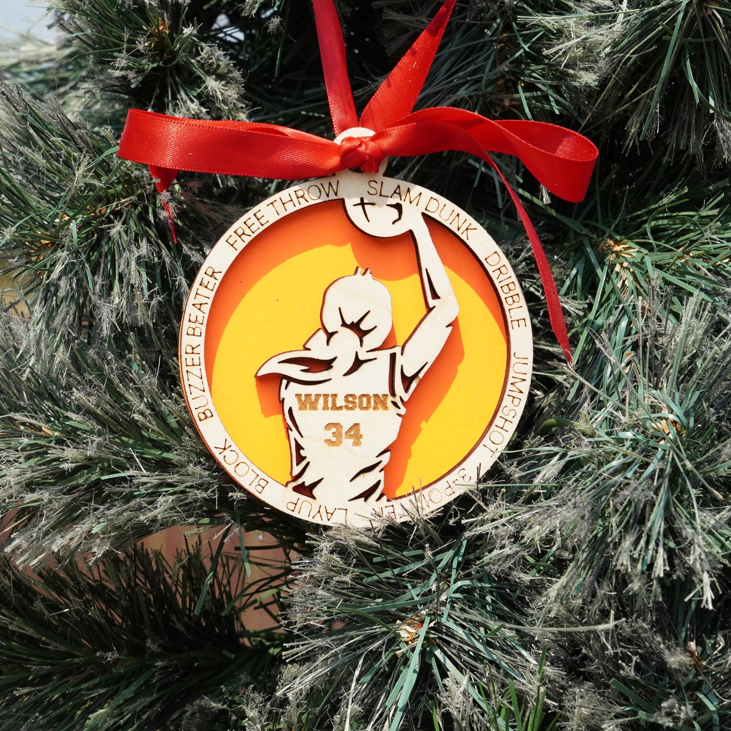 Decorative basketball ornament with a red ribbon on a Christmas tree.