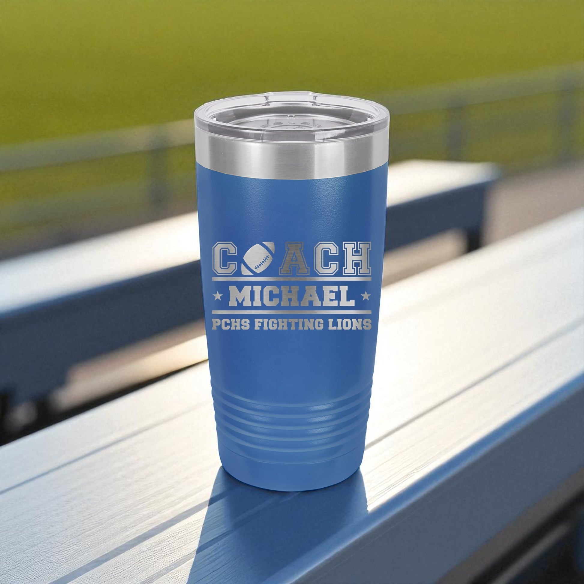 Blue insulated tumbler with engraved text on a wooden surface