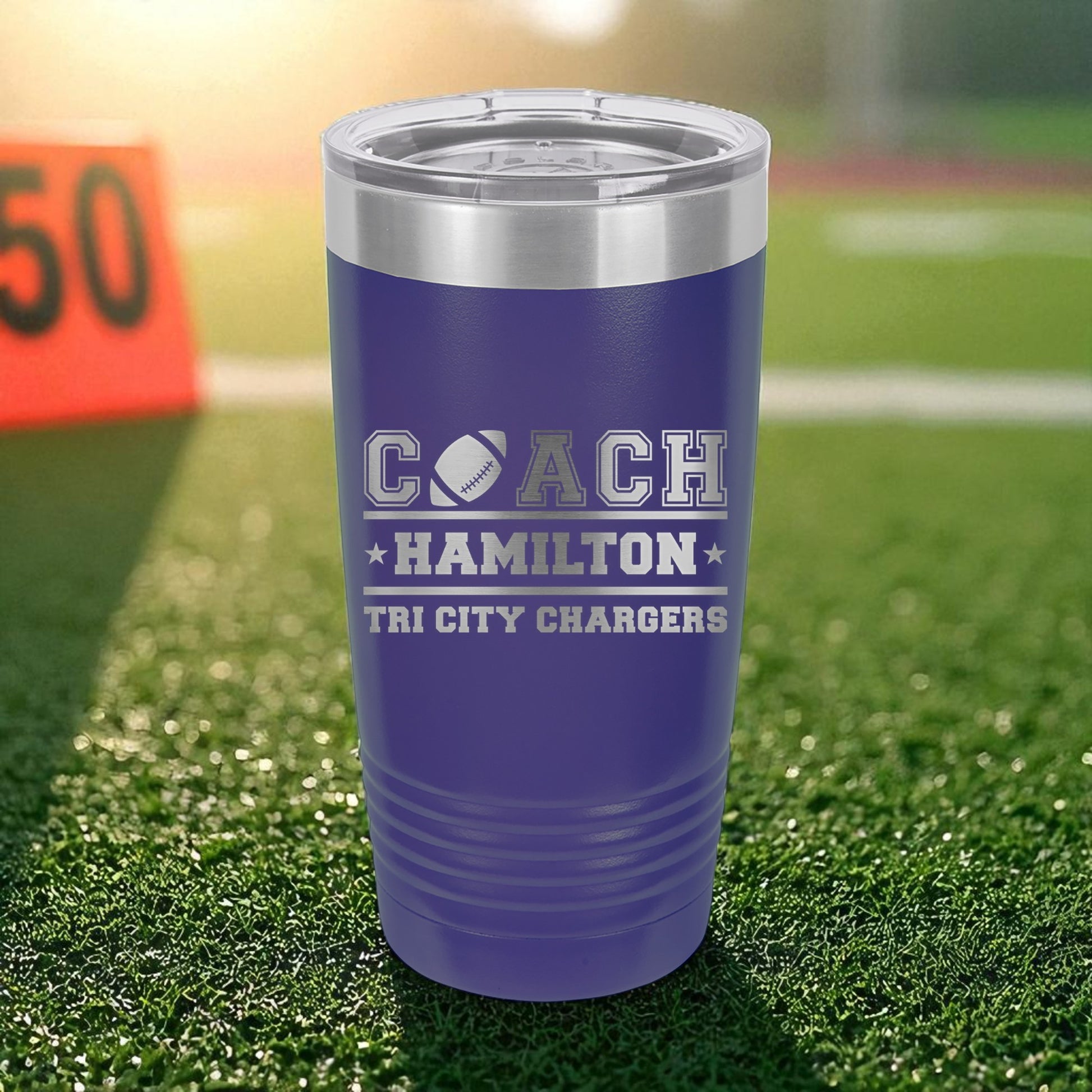 Purple tumbler with 'Coach Hamilton Tri City Chargers' text on a grass field background