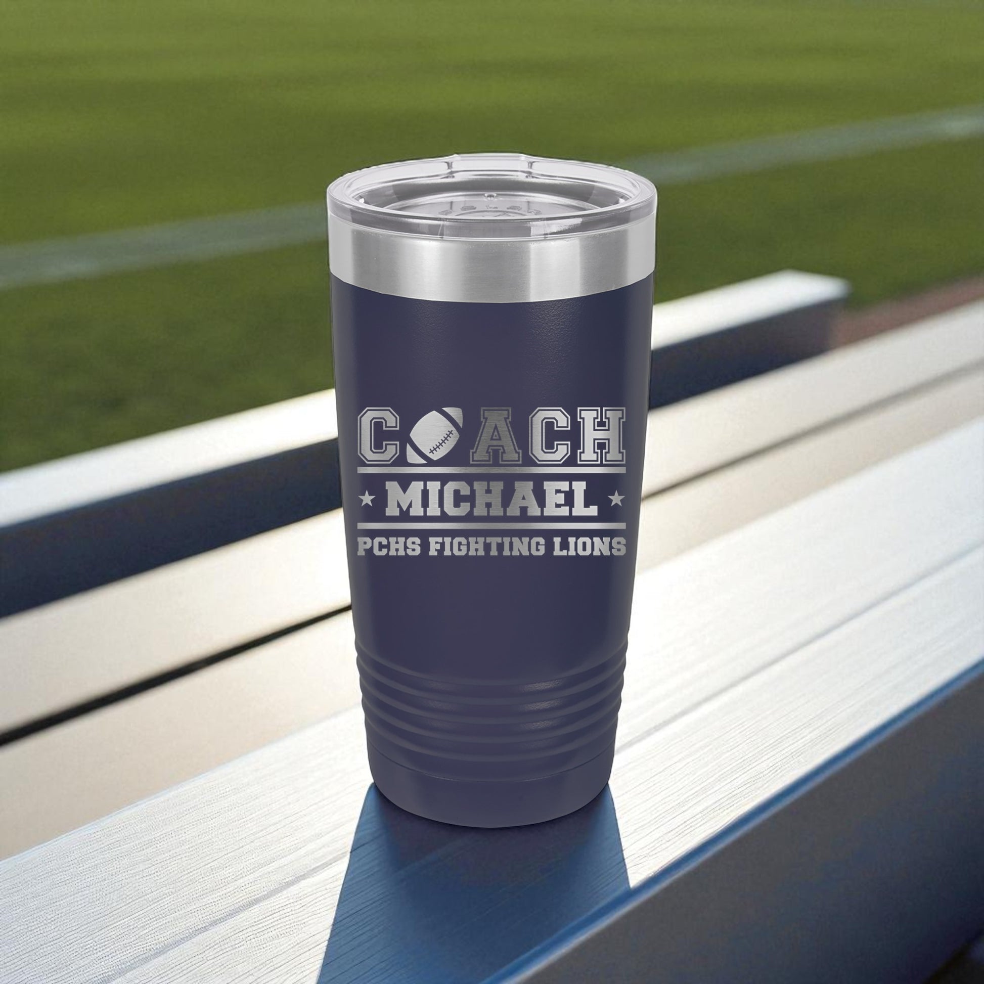 Navy blue tumbler with 'Coach Michael' and 'PCHS Fighting Lions' text on a sports field background