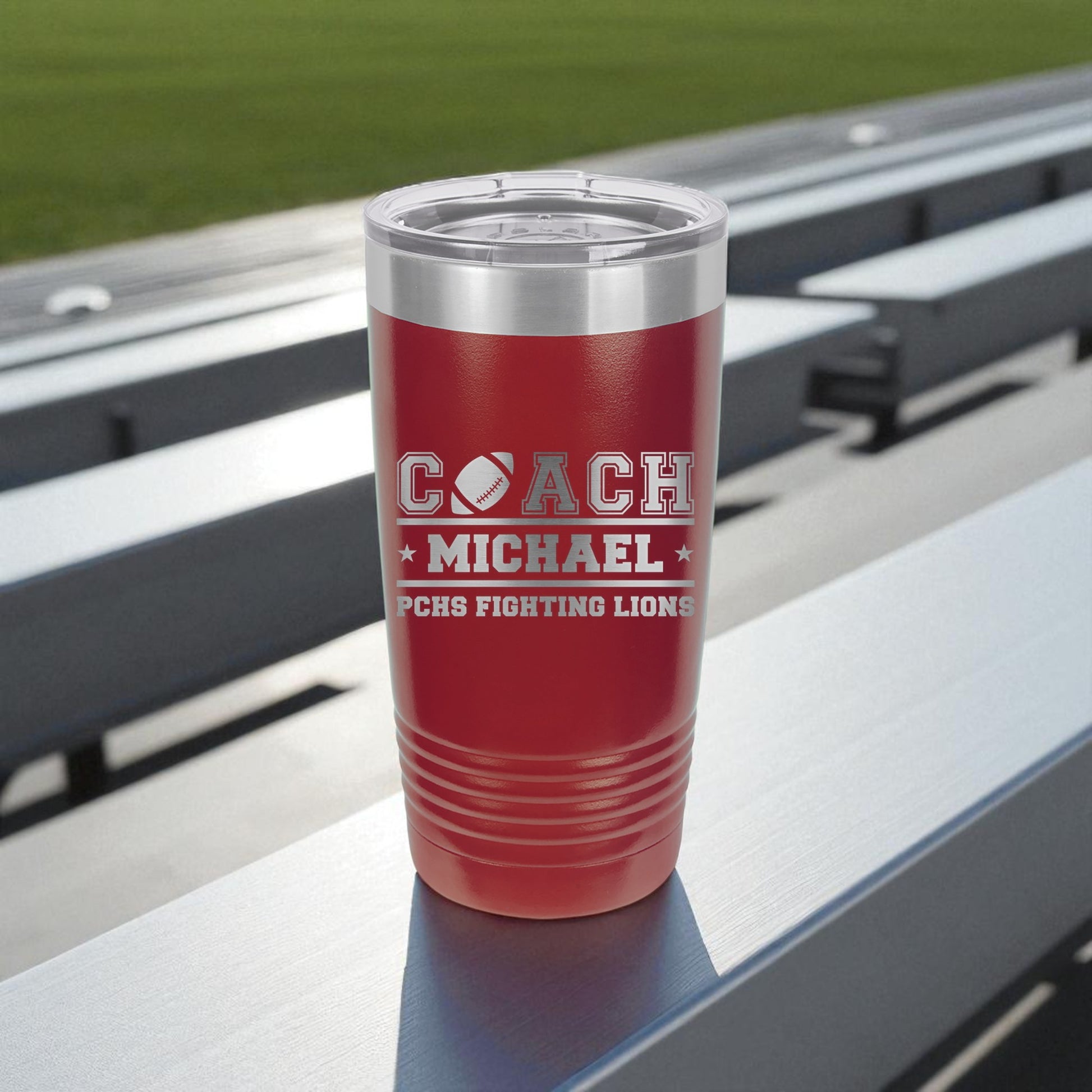 Red insulated tumbler with engraved text on a metal surface