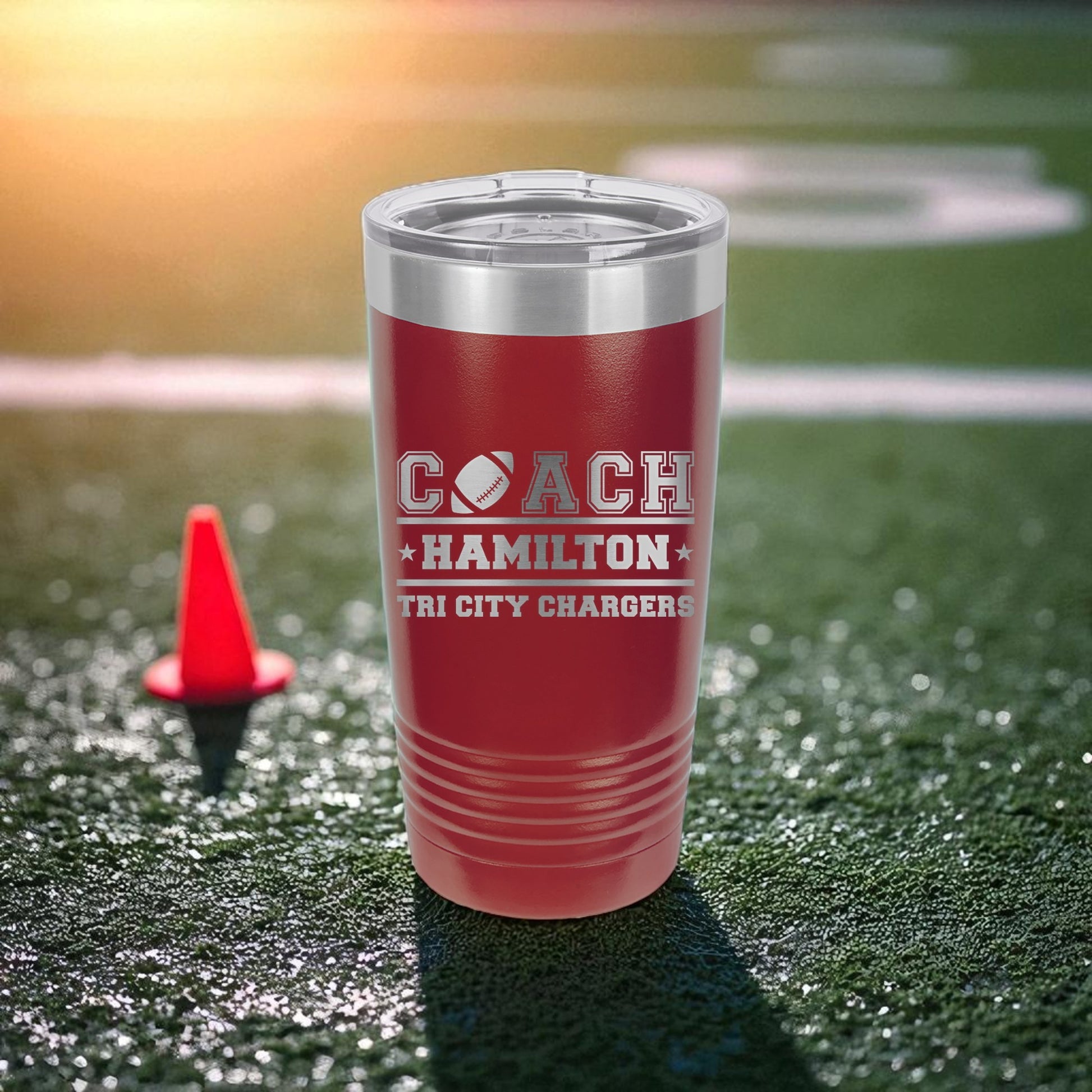Red tumbler with 'Coach Hamilton Tri City Chargers' text on a football field.