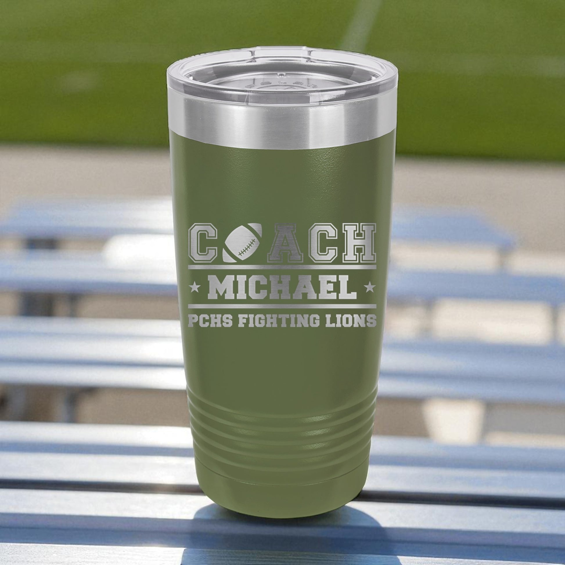 Green insulated tumbler with engraved text on a metal surface