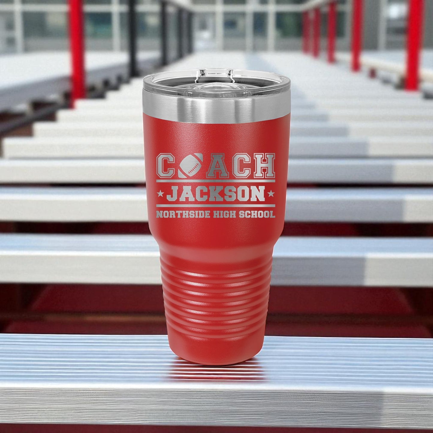 Red tumbler with 'Coach Jackson' text on bleachers