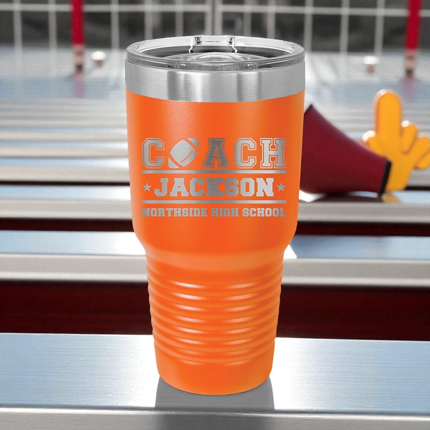 Orange tumbler with 'Coach Jackson' text on a sports field background