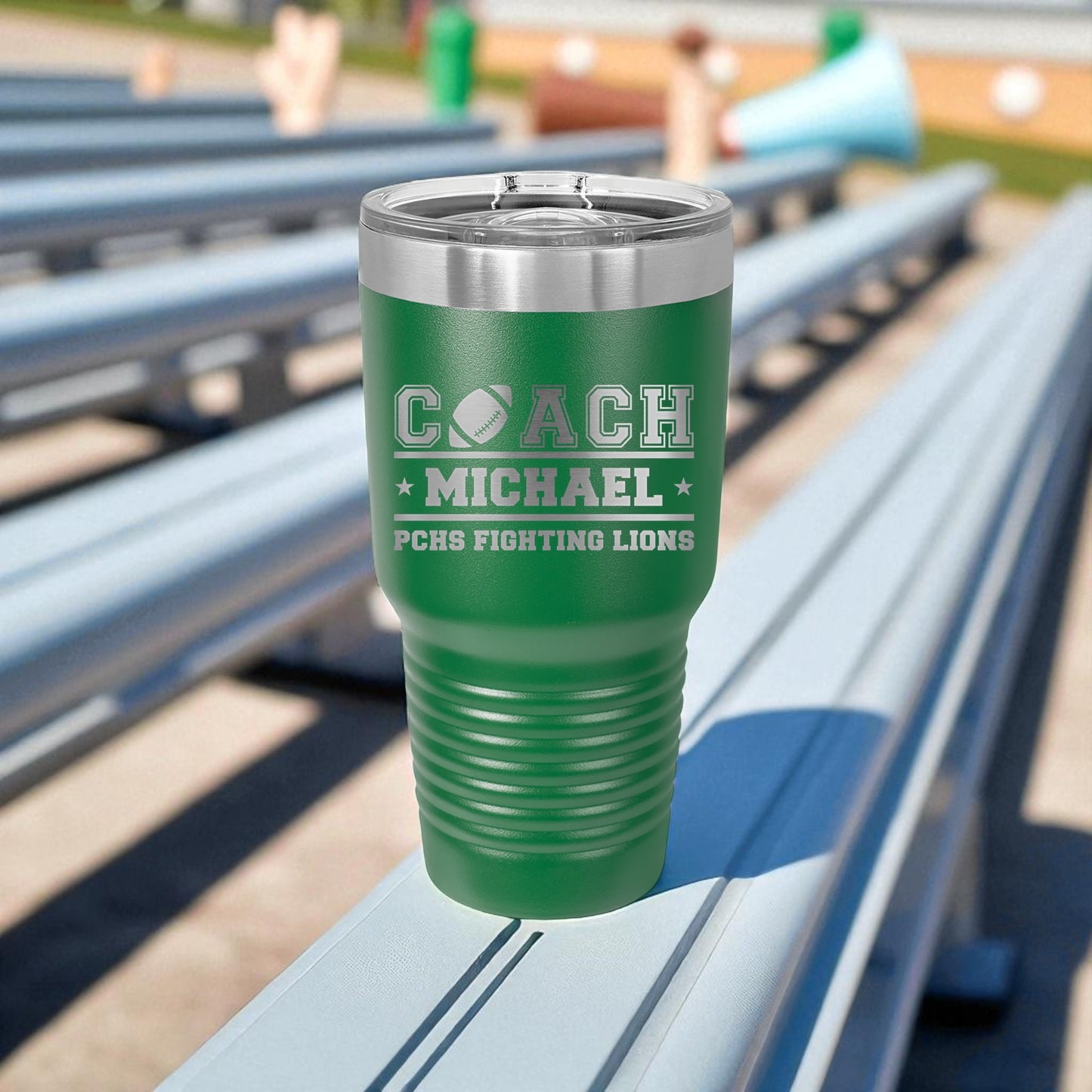 Green tumbler with engraved text on a metal bleacher