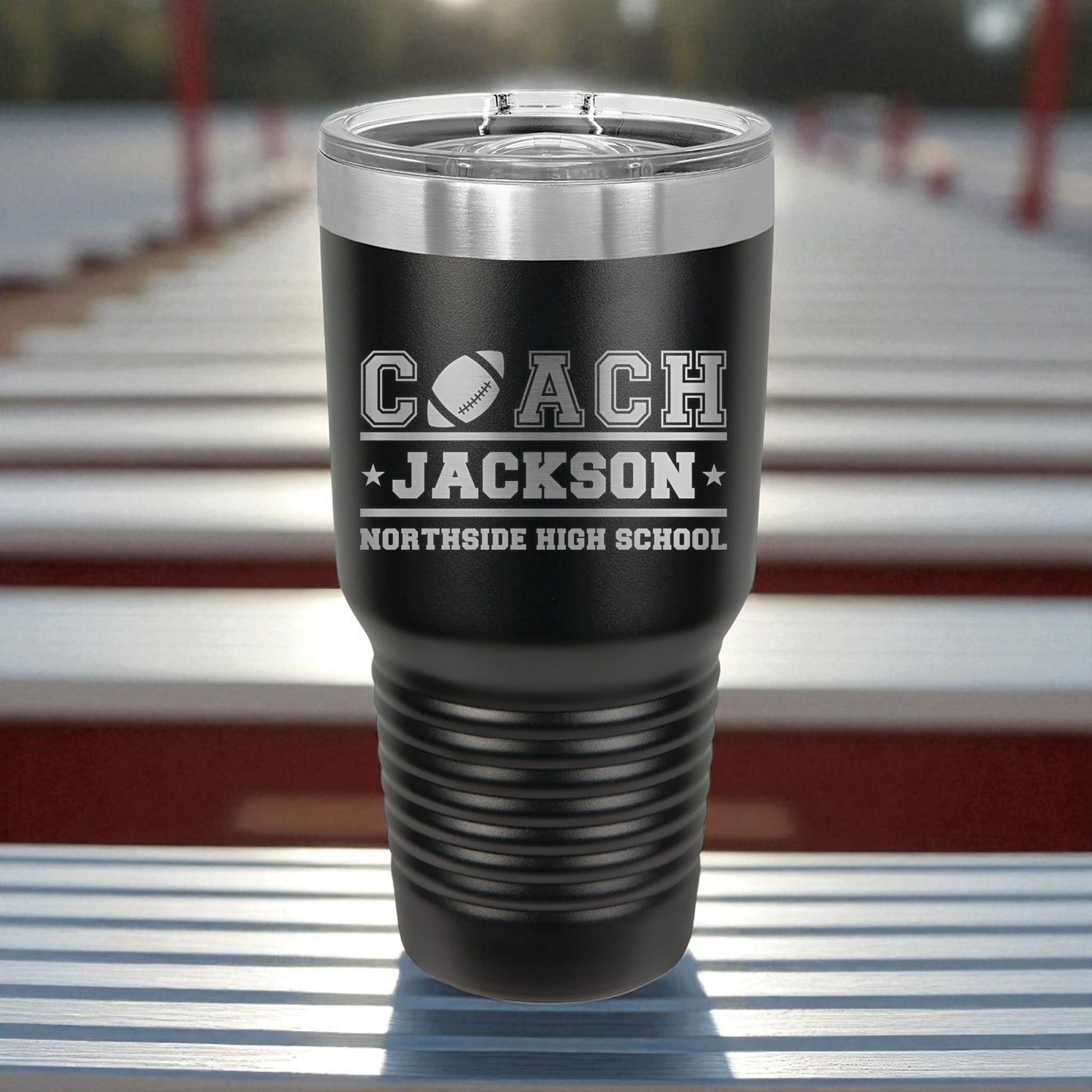 Black tumbler with 'Coach Jackson Northside High School' engraving on a metallic surface.
