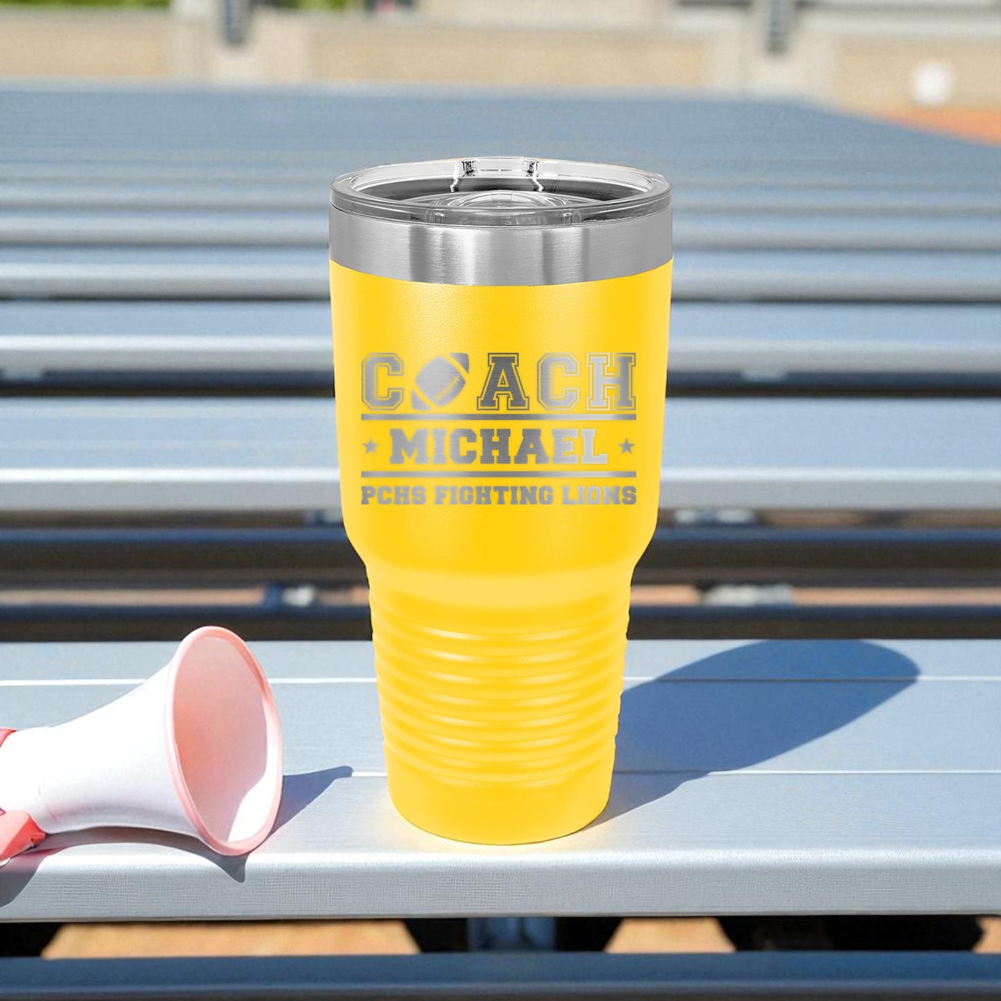 Yellow tumbler with engraved text on a metal surface