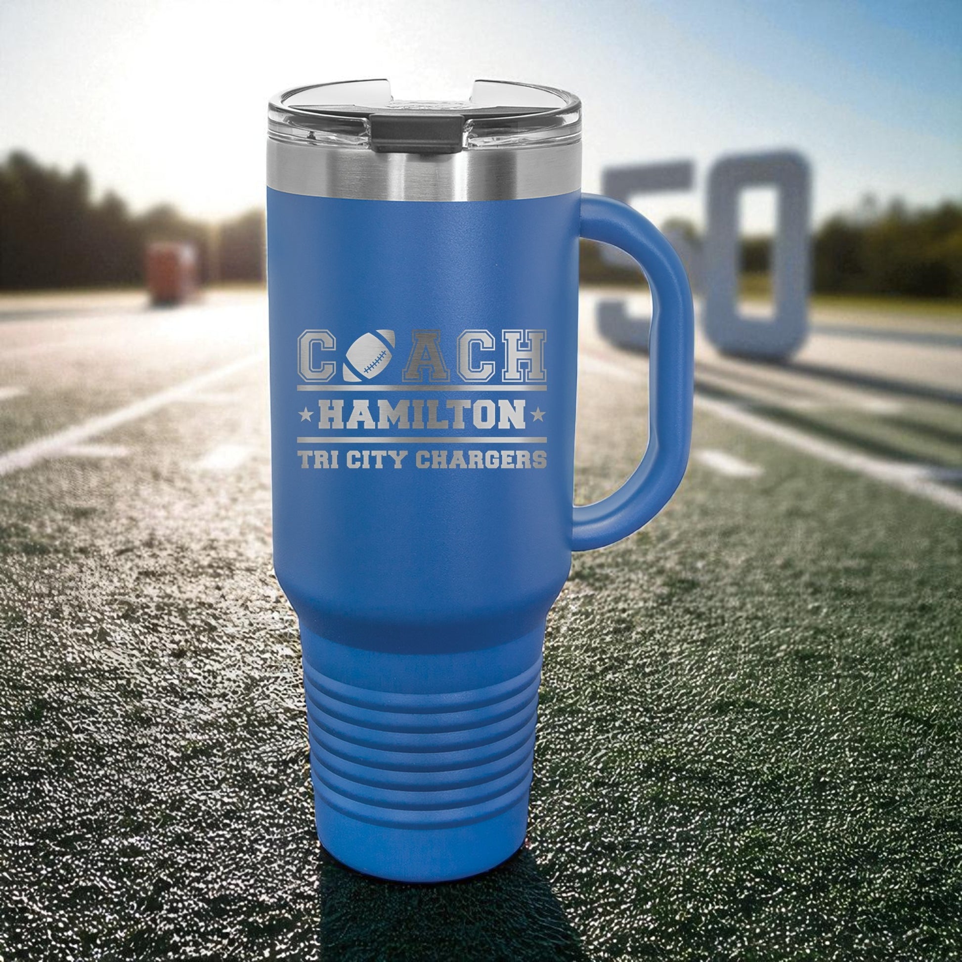 Blue travel mug with 'Coach Hamilton' text on a sports field