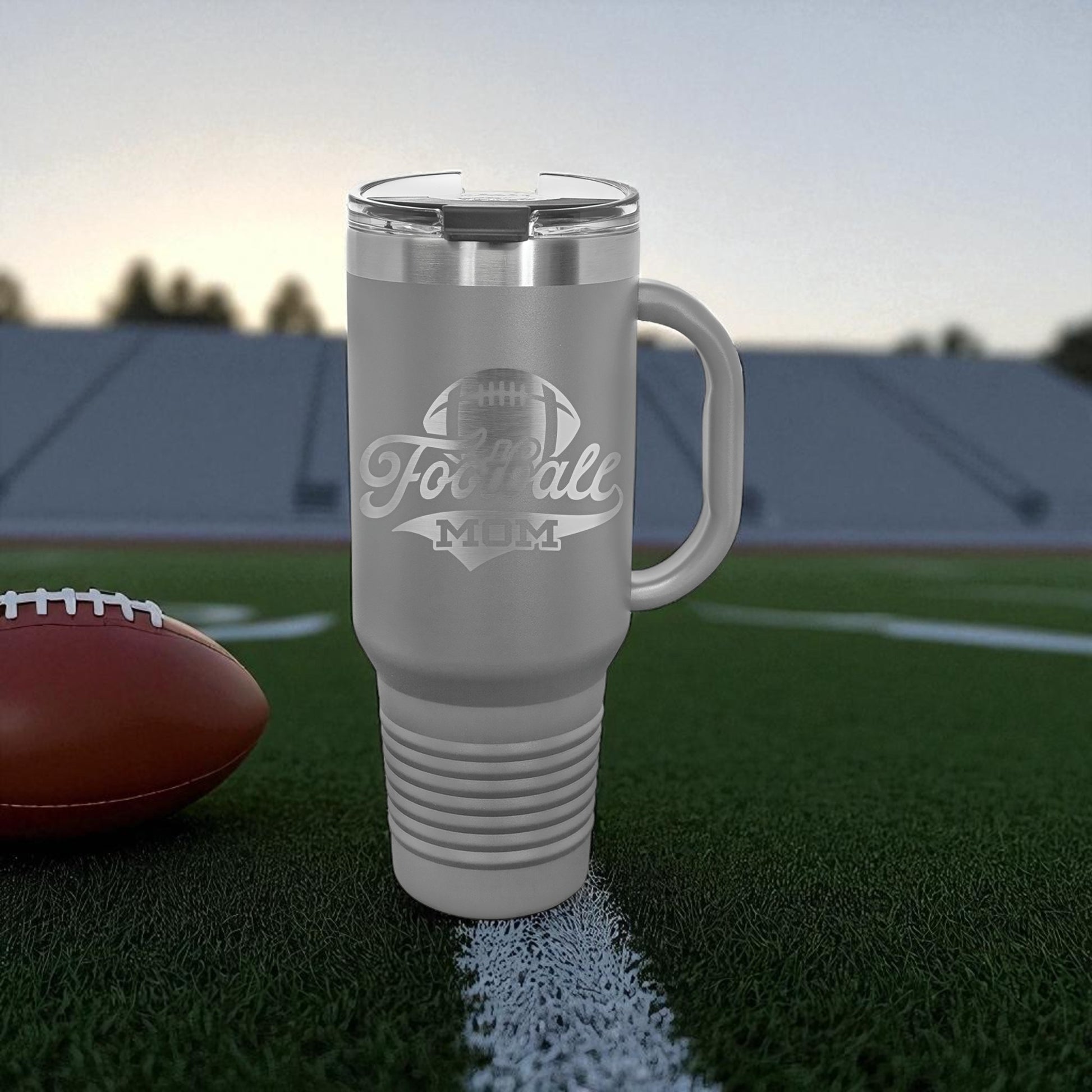 Gray travel mug with 'Football Mom' text on a football field