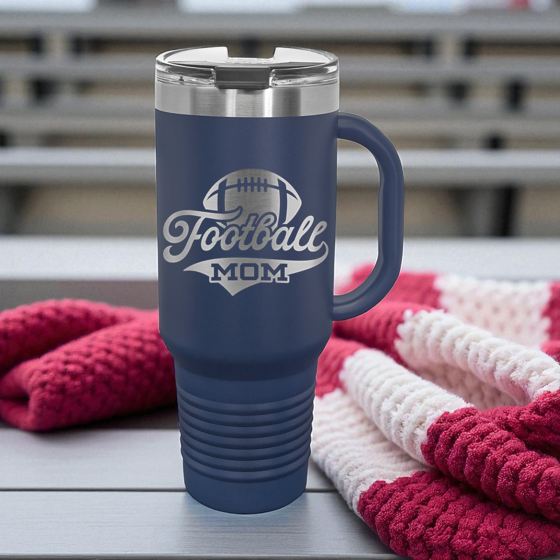 Navy blue travel mug with 'Football Mom' text on a wooden surface with knitted items.