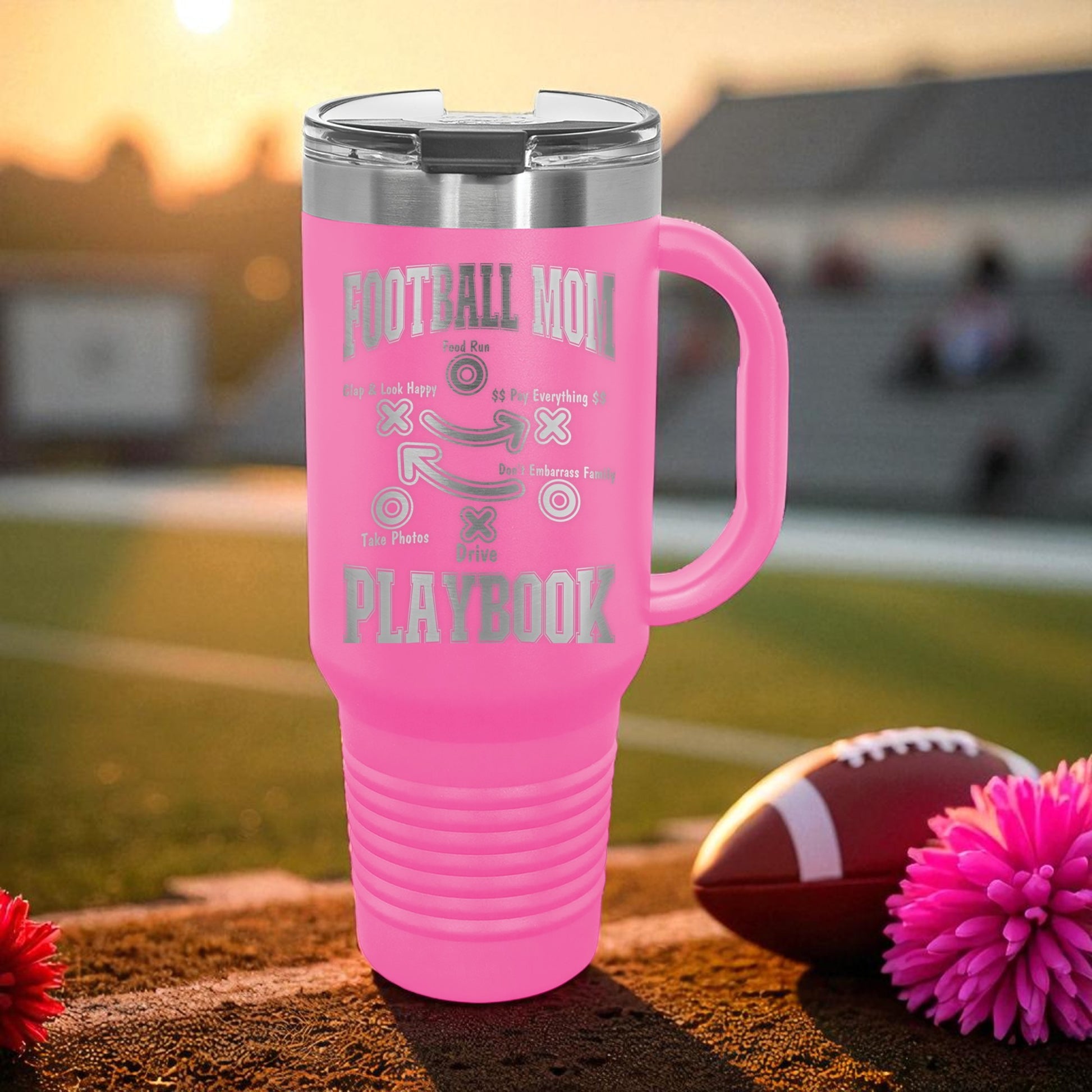 Pink travel mug with 'Football Mom' text on a football field background