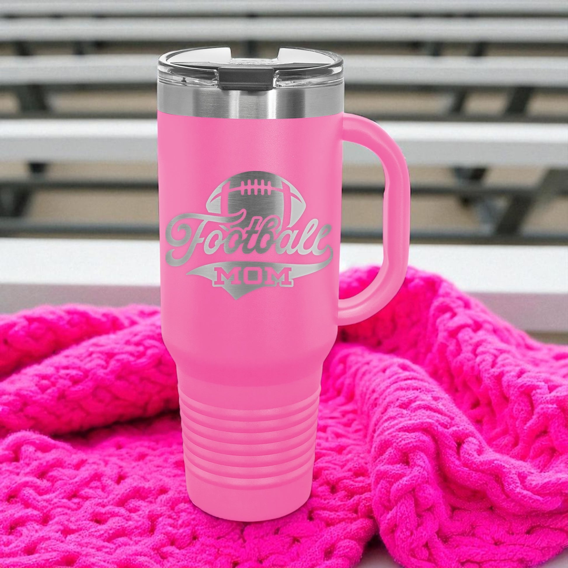 Pink travel mug with 'Football Mom' text on a pink blanket