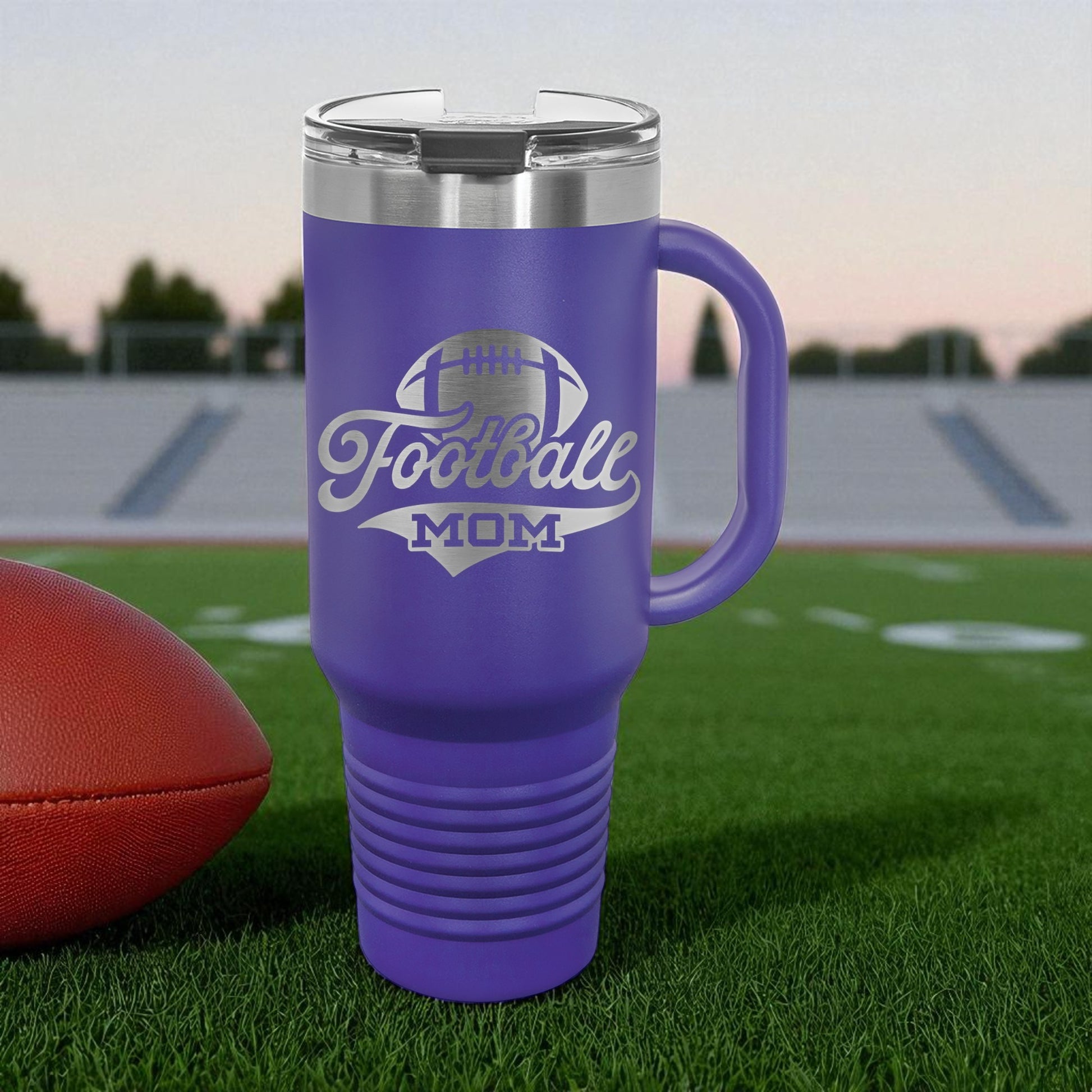 Purple travel mug with 'Football Mom' text on a football field