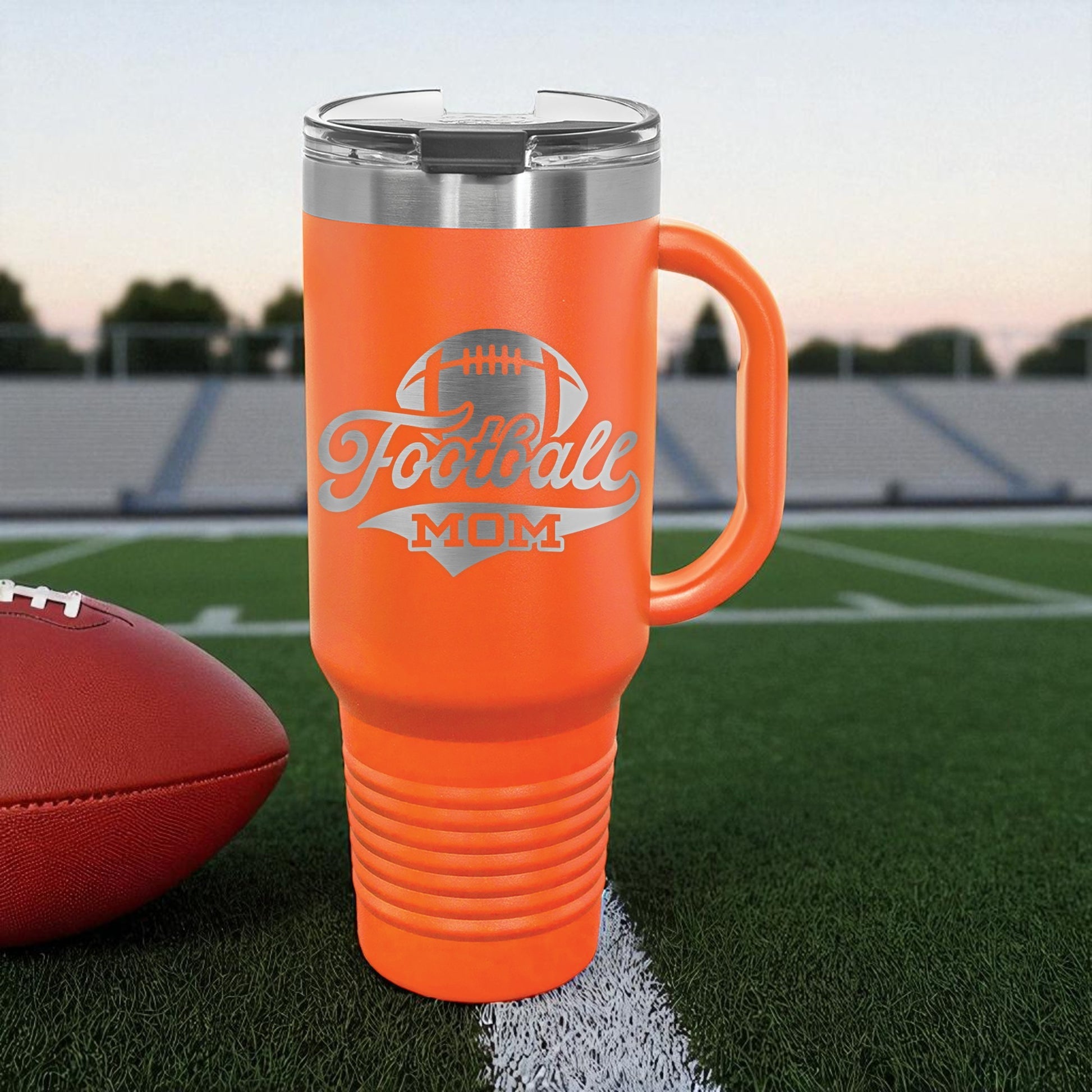 Orange mug with 'Football Mom' text on a football field