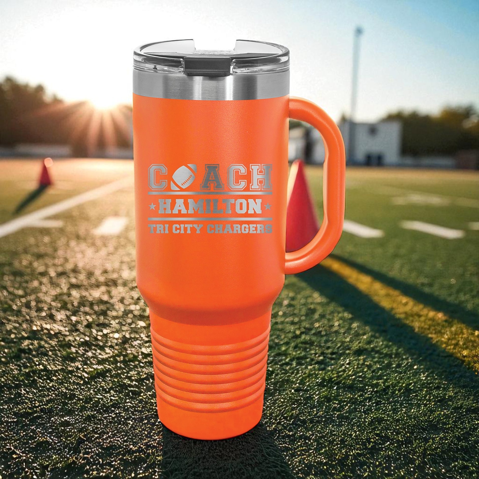Orange travel mug with 'Coach Hamilton Tri City Chargers' text on a football field.