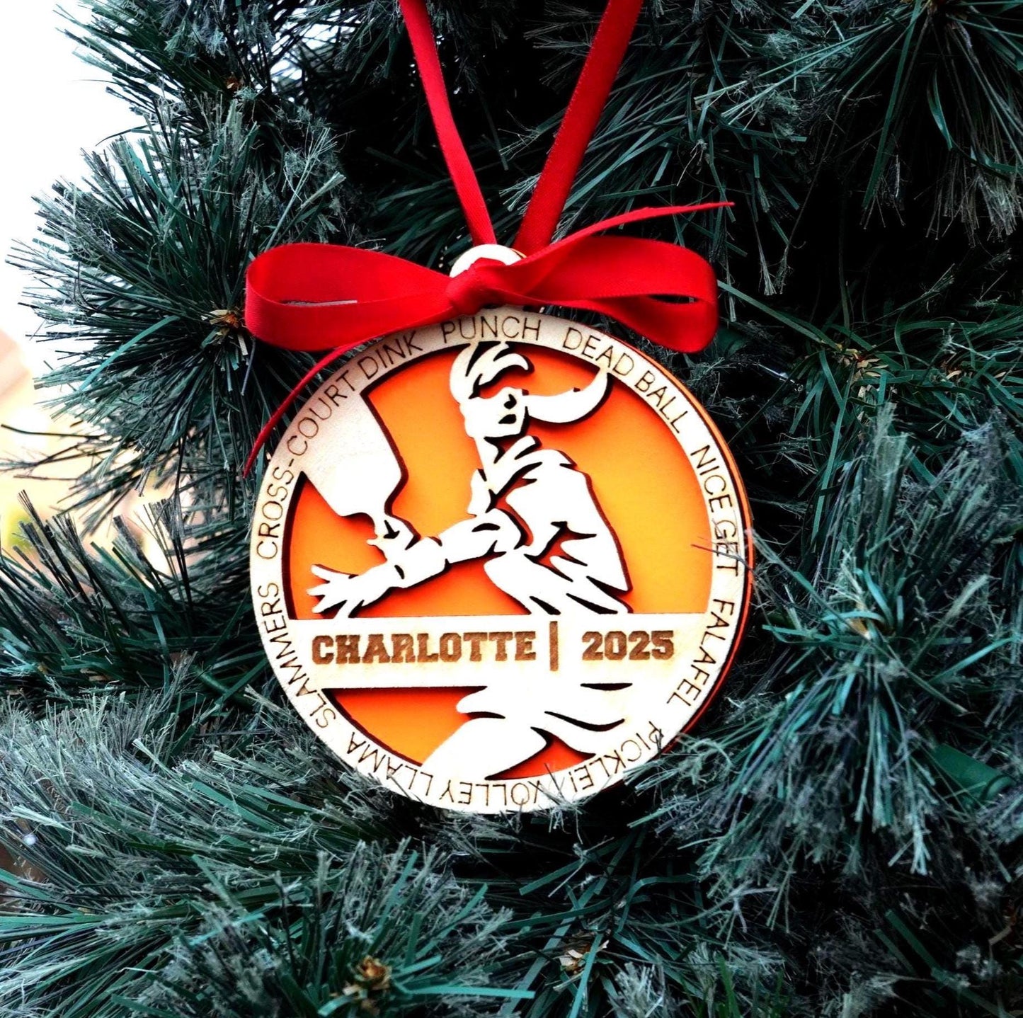 Christmas ornament with a red ribbon on a tree, featuring the text 'Charlotte 2025'. Pickleball Ornament