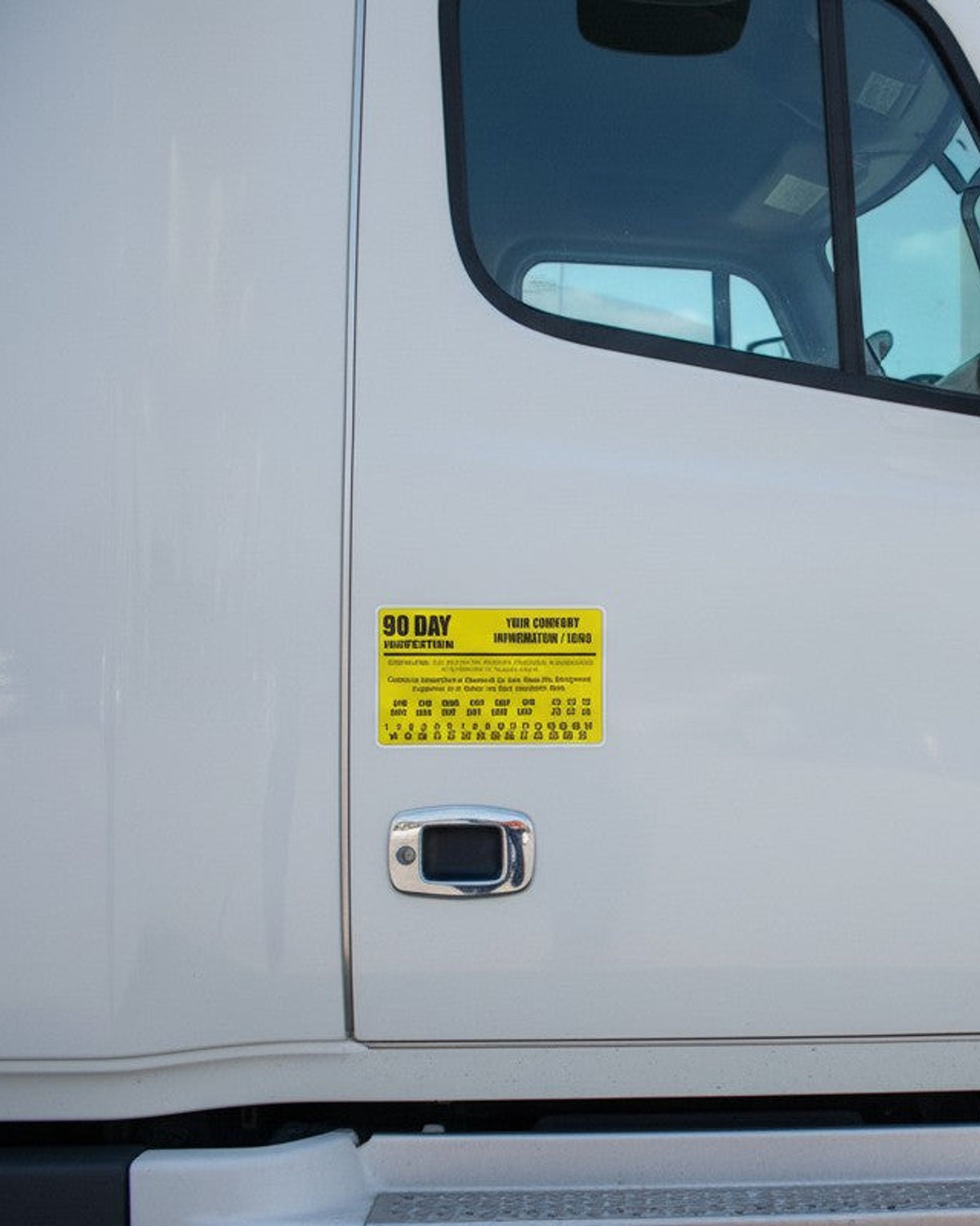 Yellow 90 day BIT inspection label applied to a white semi truck door, custom company name decal for California fleets