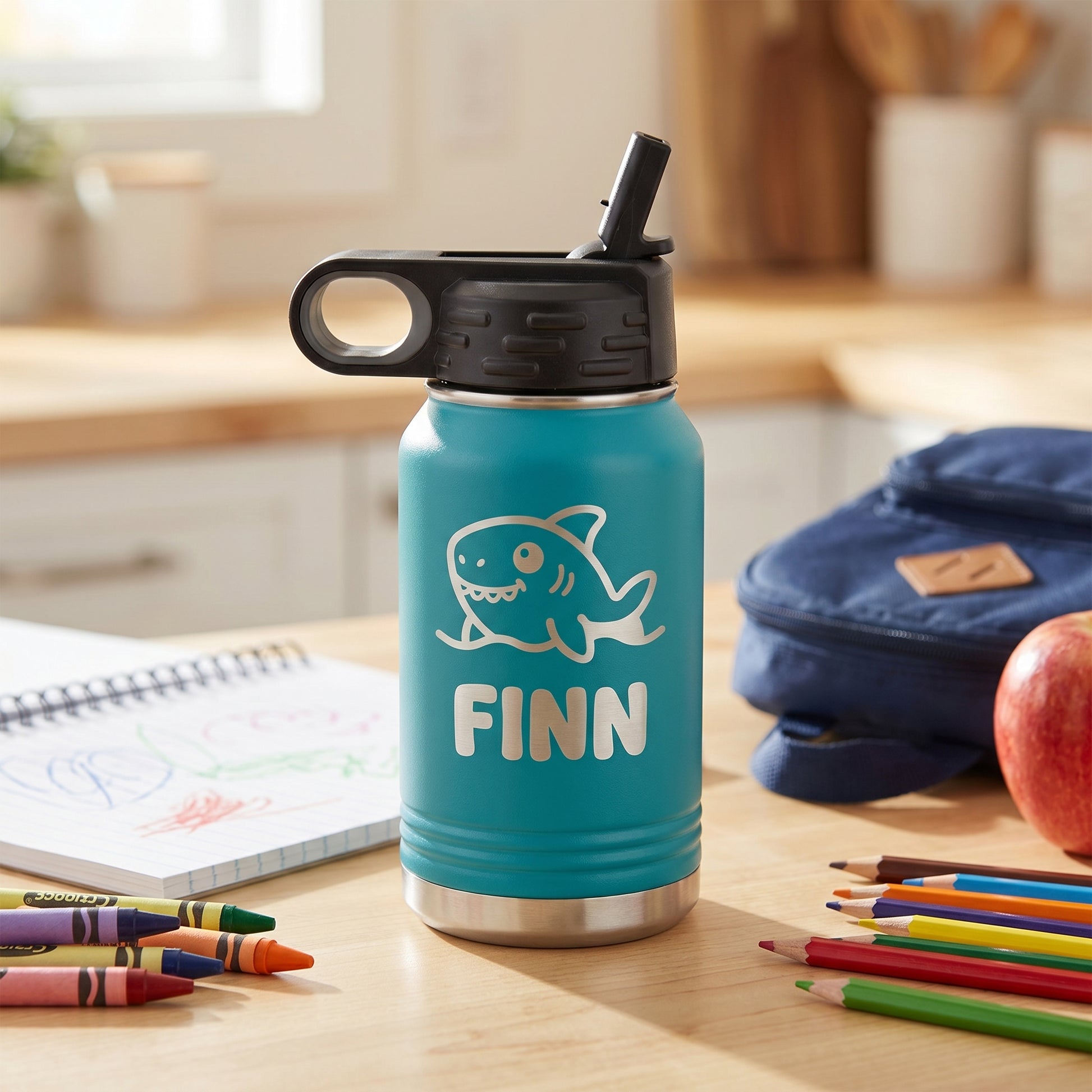Toddler holding teal personalized 12oz water bottle with engraved shark design