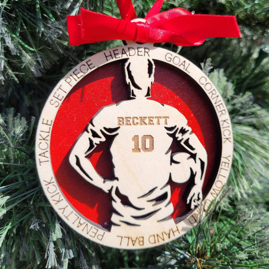 Decorative sports-themed ornament with a red ribbon on a Christmas tree. soccer player christmas gift, christmas ornament for soccer player, personalized soccer player christmas ornament
