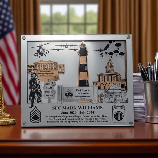 Plaque with military-themed design on a desk with an American flag in the background, pcs gift for Fort Bragg
