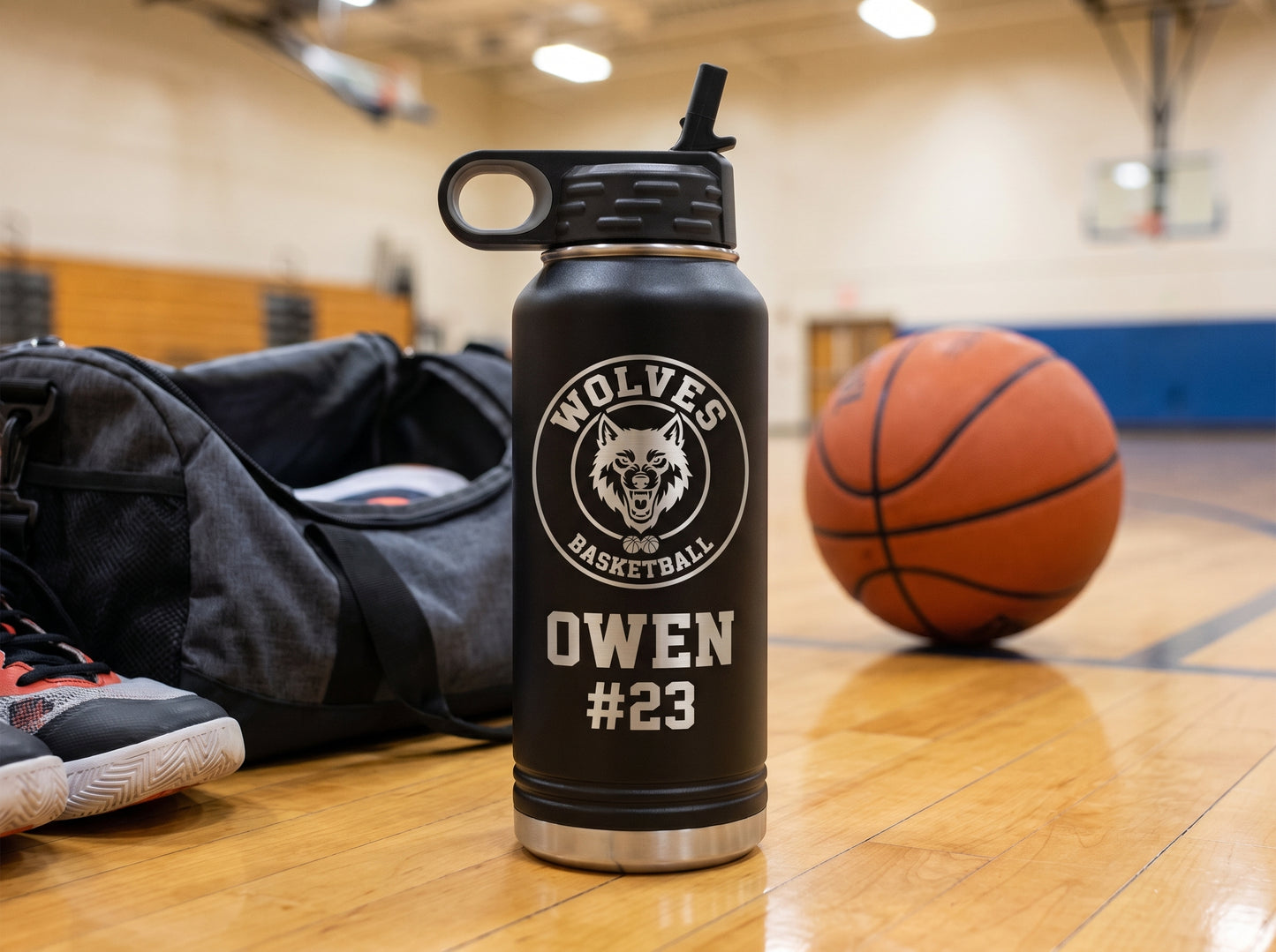 black basketball team water bottle on gym duffel bag with sneakers and ball courtside