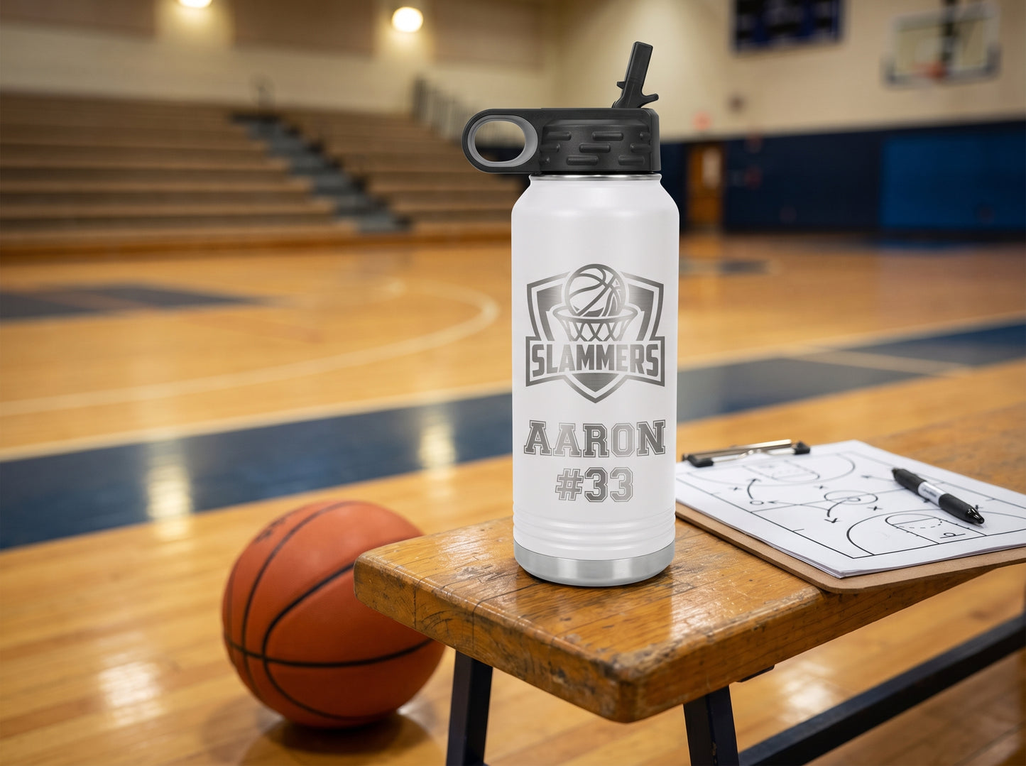 white engraved basketball water bottle next to coach tactics clipboard courtside bench
