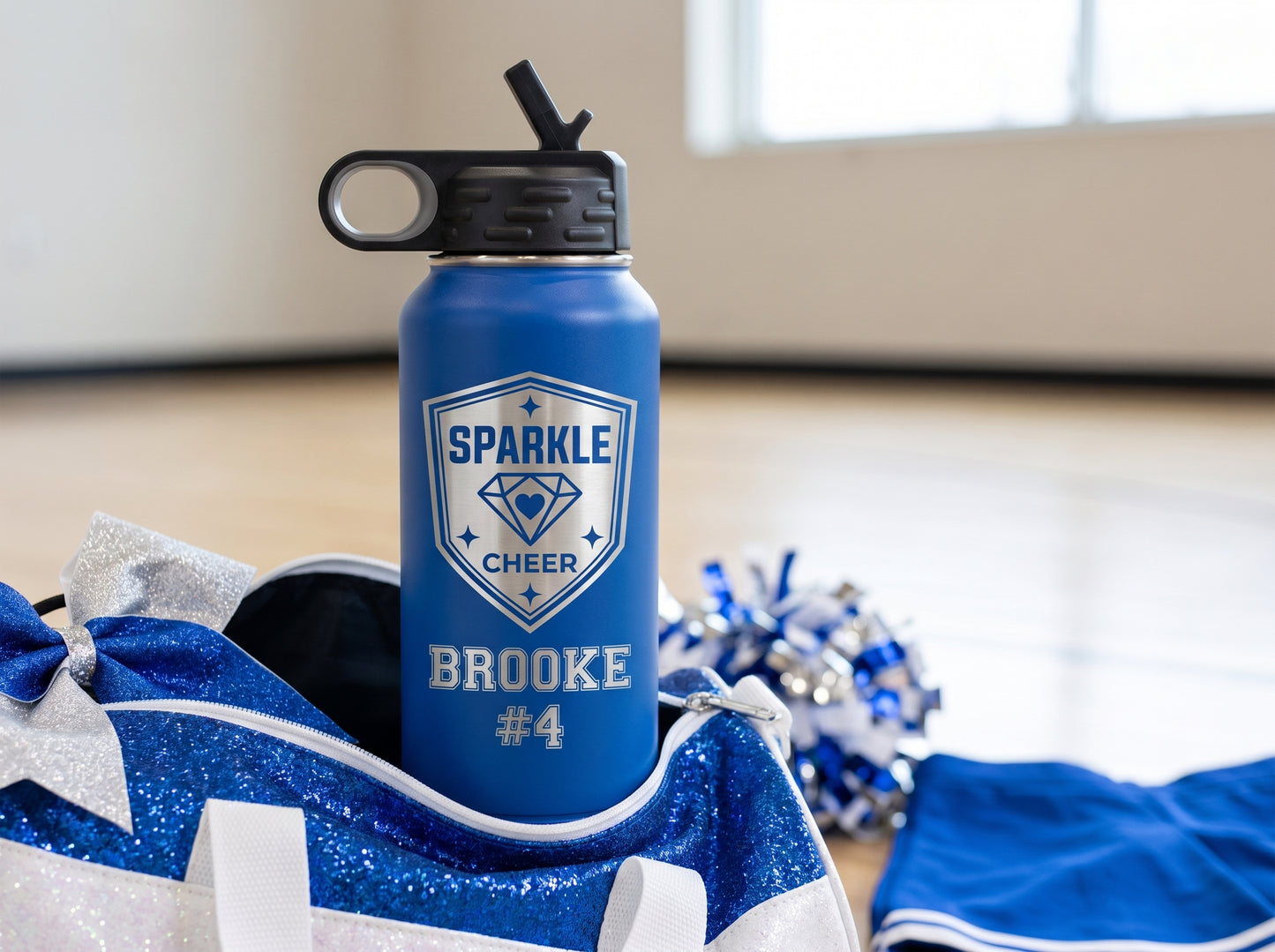 royal blue cheer team water bottle on sparkly cheer duffel bag with pom-poms and cheer bow