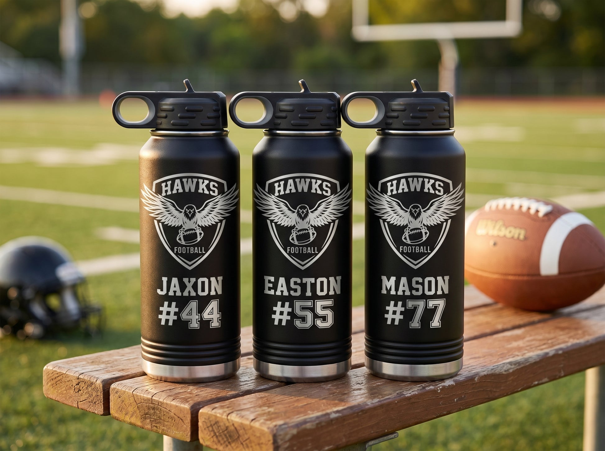 three black football team water bottles with hawks crest and individual player jersey numbers