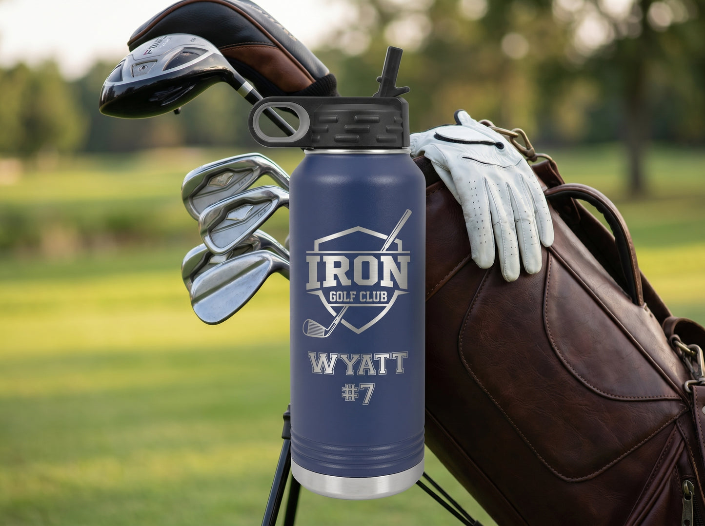 navy golf team water bottle next to leather golf bag with clubs at clubhouse