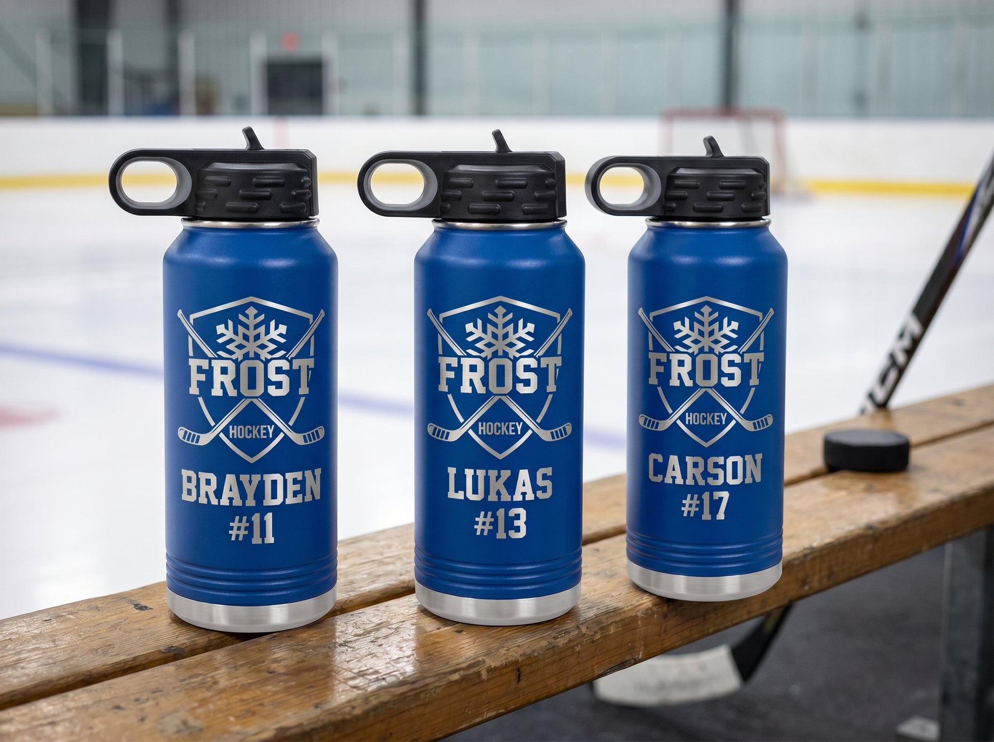 three royal blue hockey water bottles with team logo and player names lined up on bench