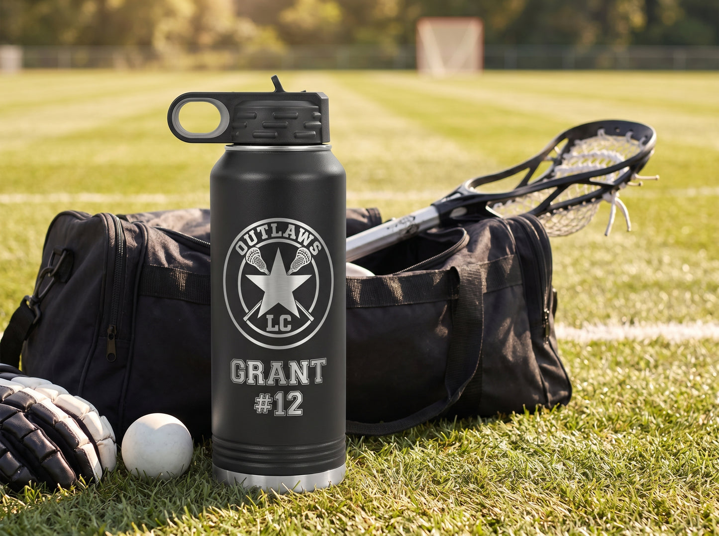 black lacrosse team water bottle on equipment gear bag with stick and ball at sideline