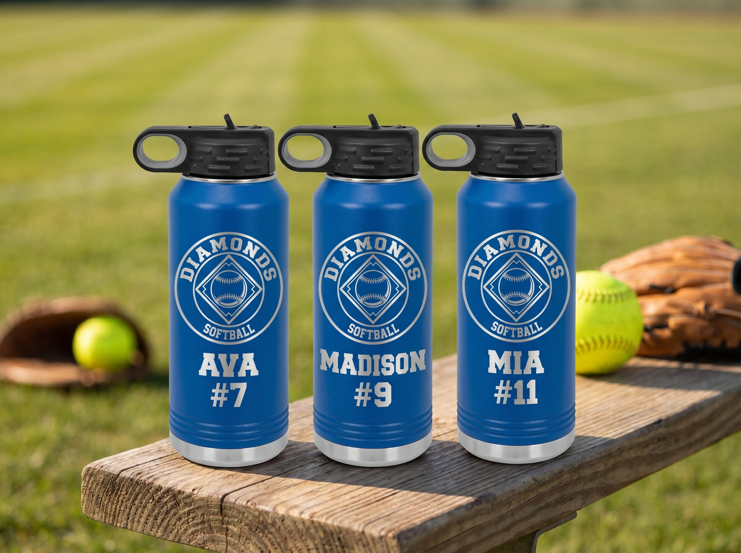 three royal blue softball water bottles with team logo and player names lined up on bench