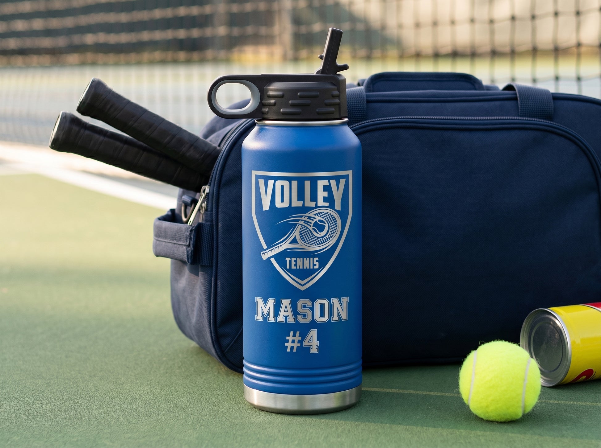 royal blue tennis team water bottle resting on racket bag with rackets and ball can courtside