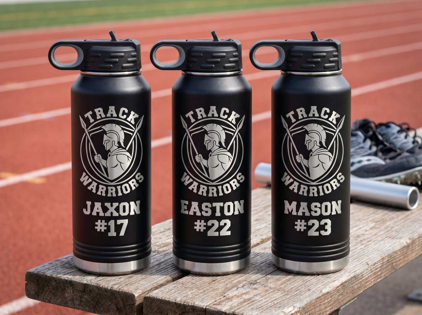 three black track and field team water bottles with team crest and individual athlete bib numbers
