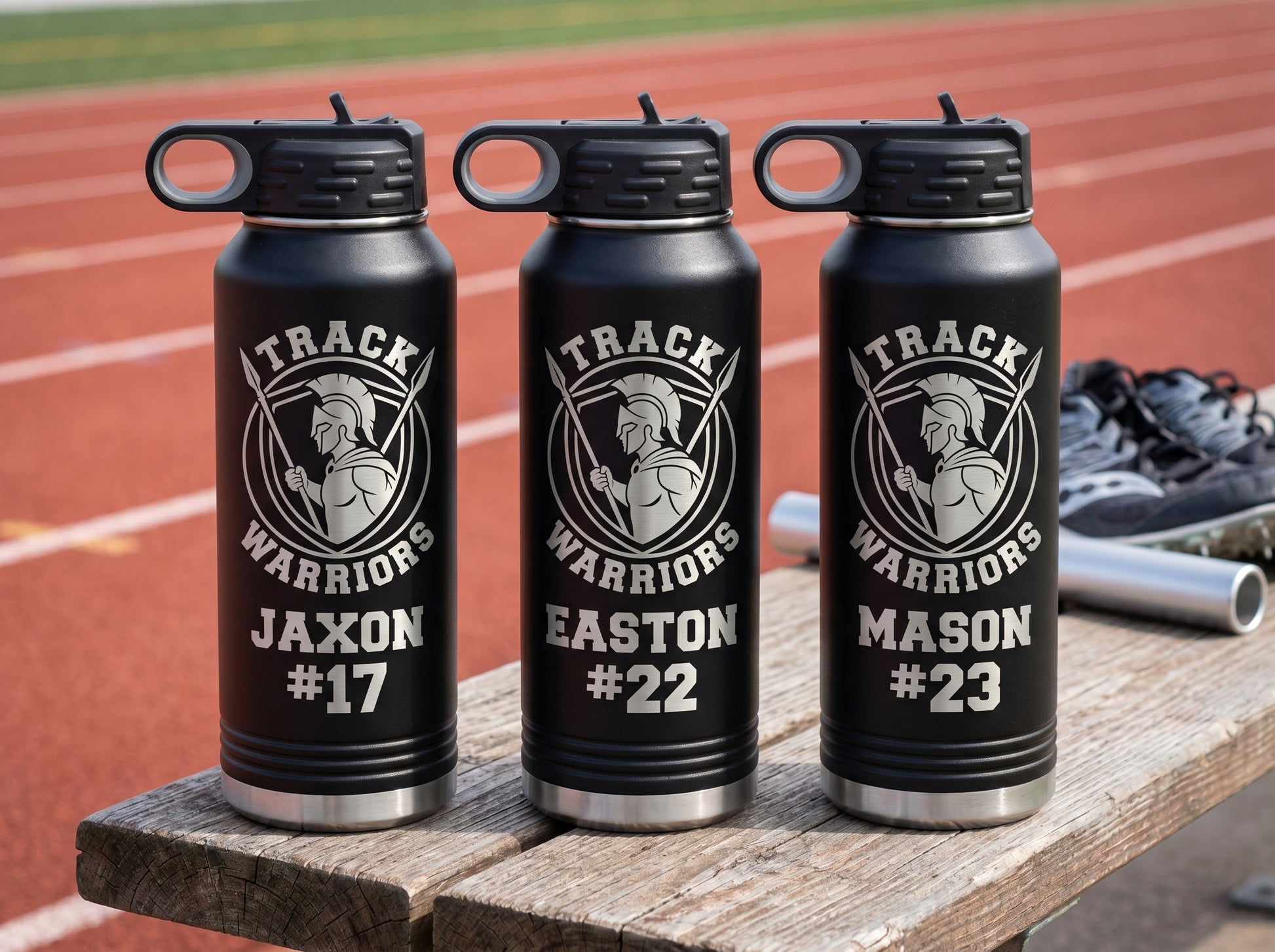 three black track and field team water bottles with team crest and individual athlete bib numbers