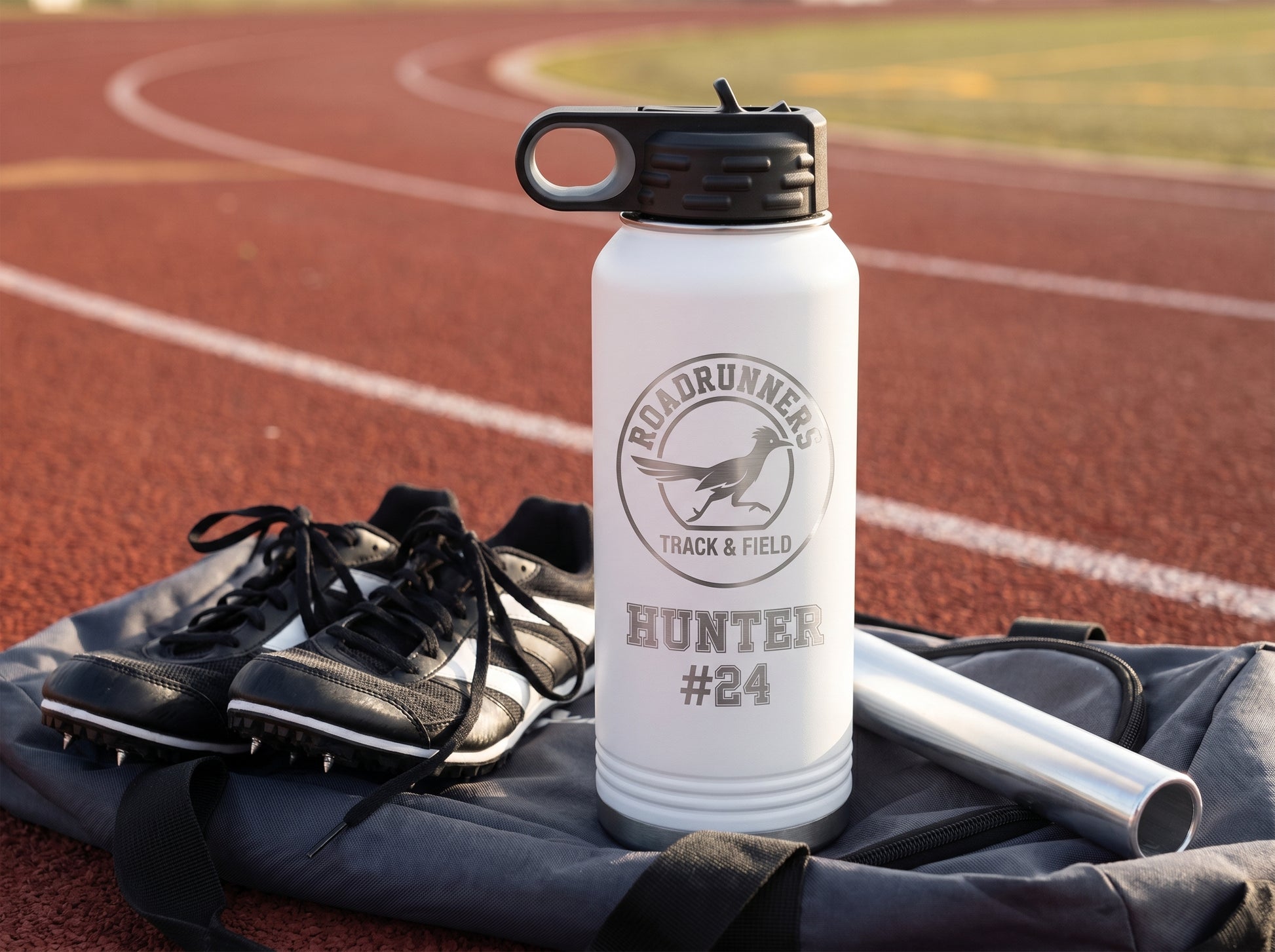 white track team water bottle on athlete gear bag with relay baton and running spikes