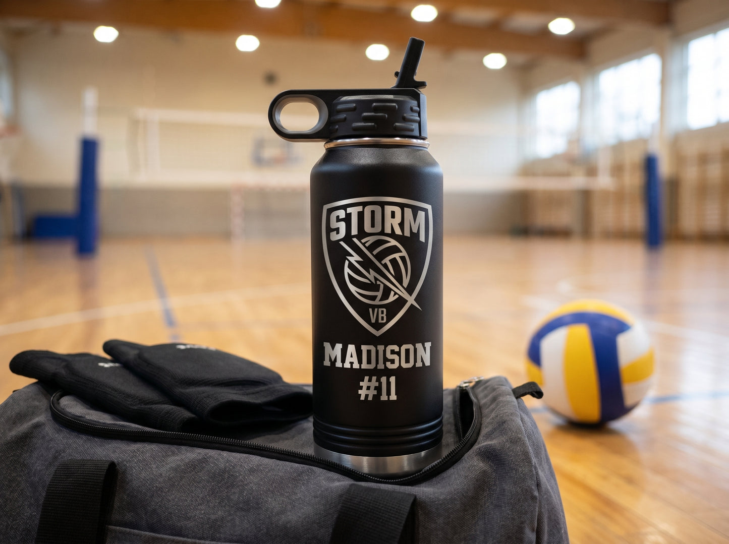 black volleyball team water bottle resting on gym duffel bag with knee pads and ball at sideline