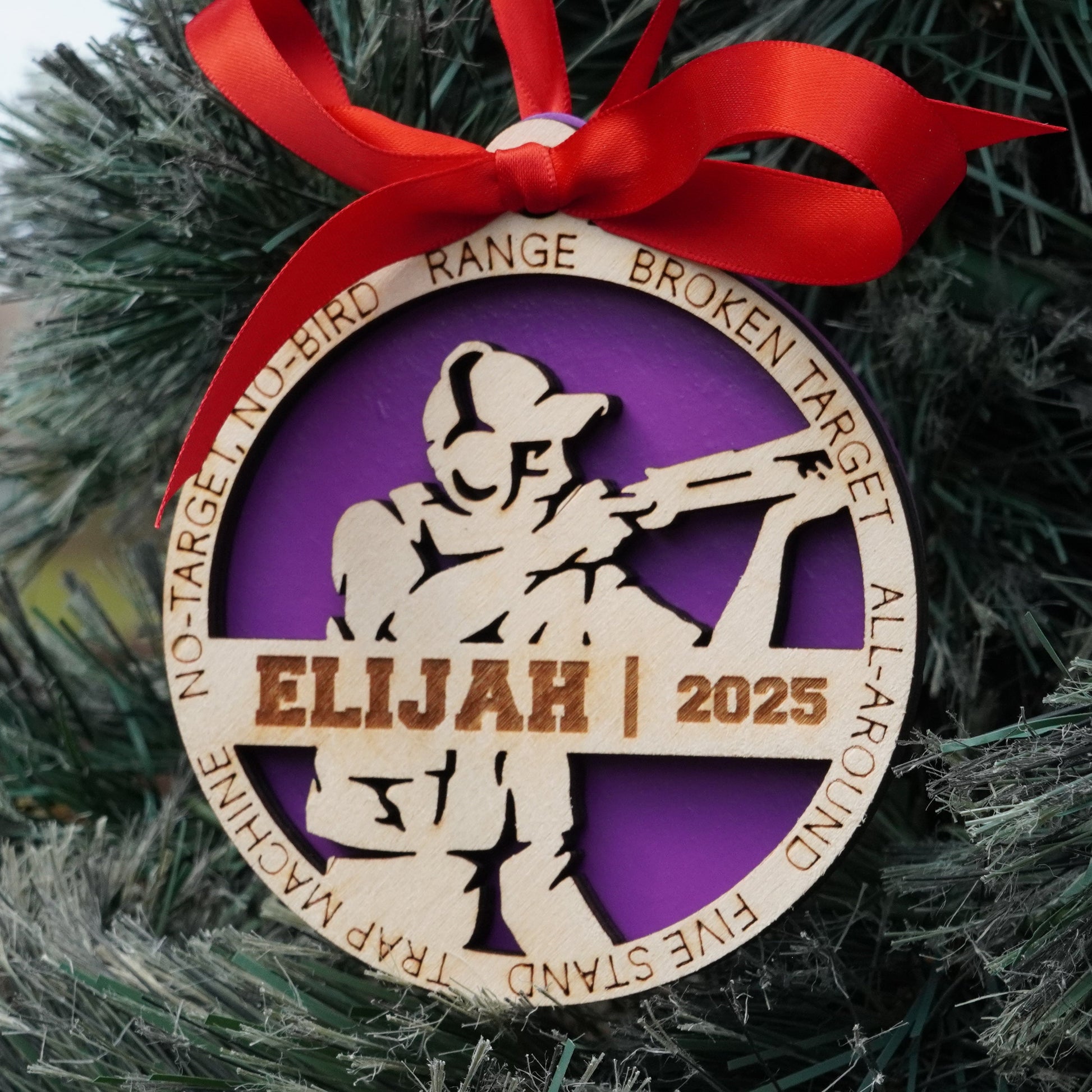 Decorative Christmas ornament with a purple and gold design, featuring the name 'Elijah' and the year '2025', hanging on a tree. Decorative Christmas ornament with a silhouette of a person holding a skeet shooting on a christmas tree, Clay Shooting Ornament, Skeet Shooting Gift, Clay Shooter Gift