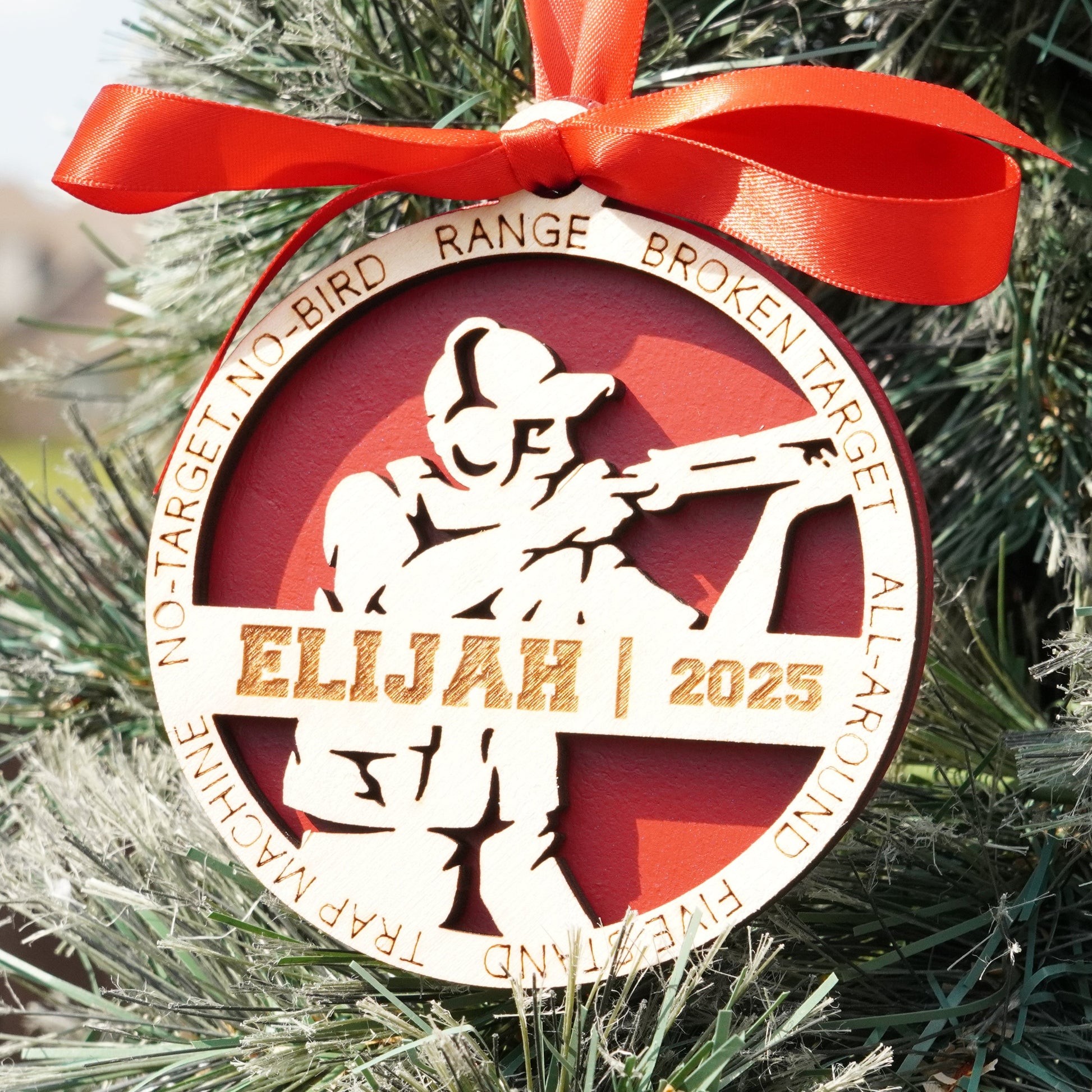 Decorative ornament with a silhouette of a person holding a gun, red ribbon, and text on a Christmas tree. Decorative Christmas ornament with a silhouette of a person holding a skeet shooting on a christmas tree, Clay Shooting Ornament, Skeet Shooting Gift, Clay Shooter Gift