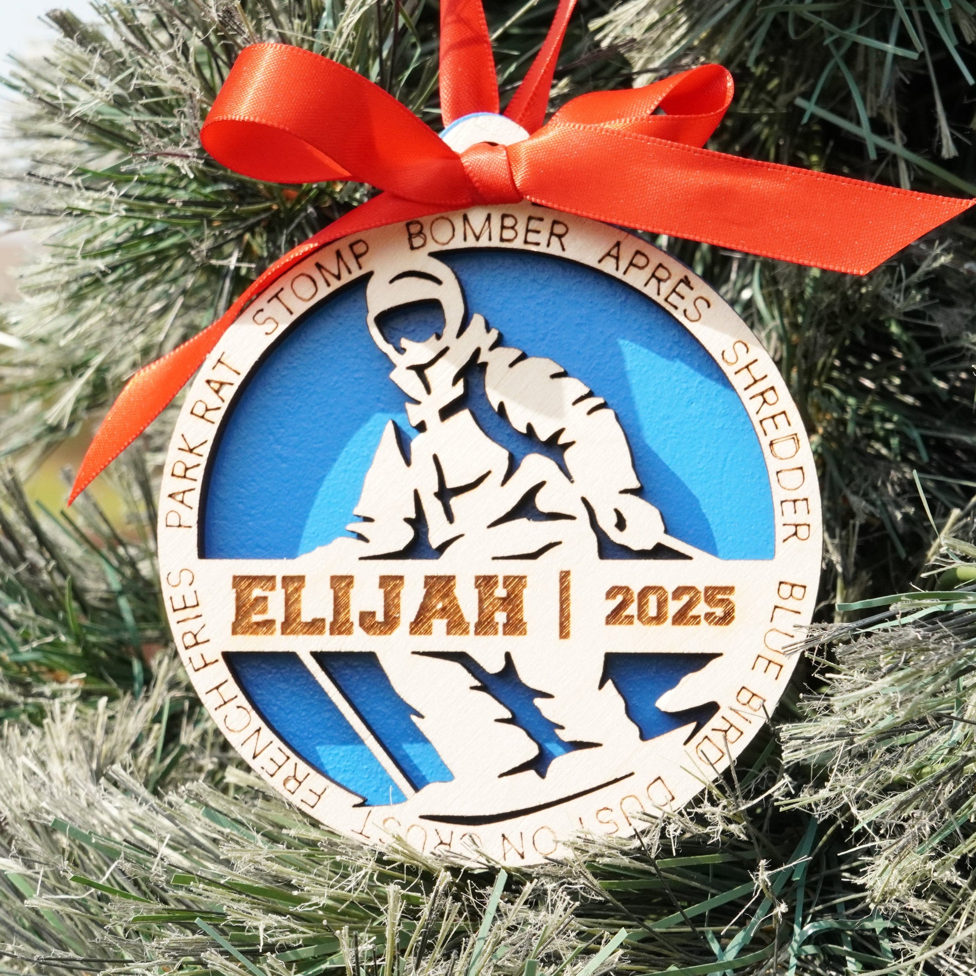 Decorative ornament with 'Elijah 2025' on a Christmas tree.