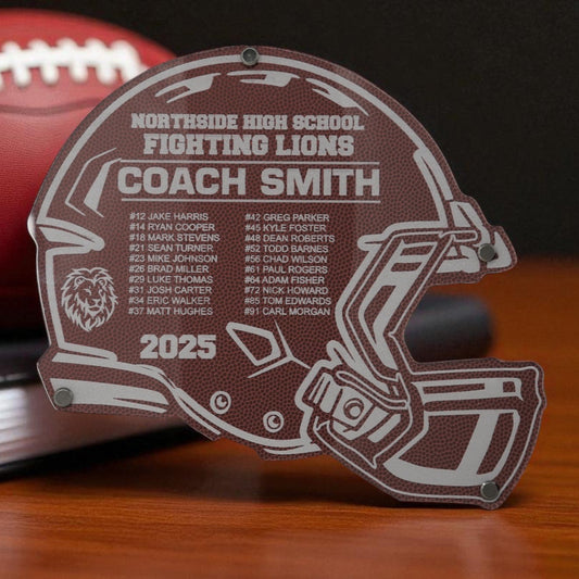 Helmet-shaped plaque with engraved text on a wooden surface with a football in the background