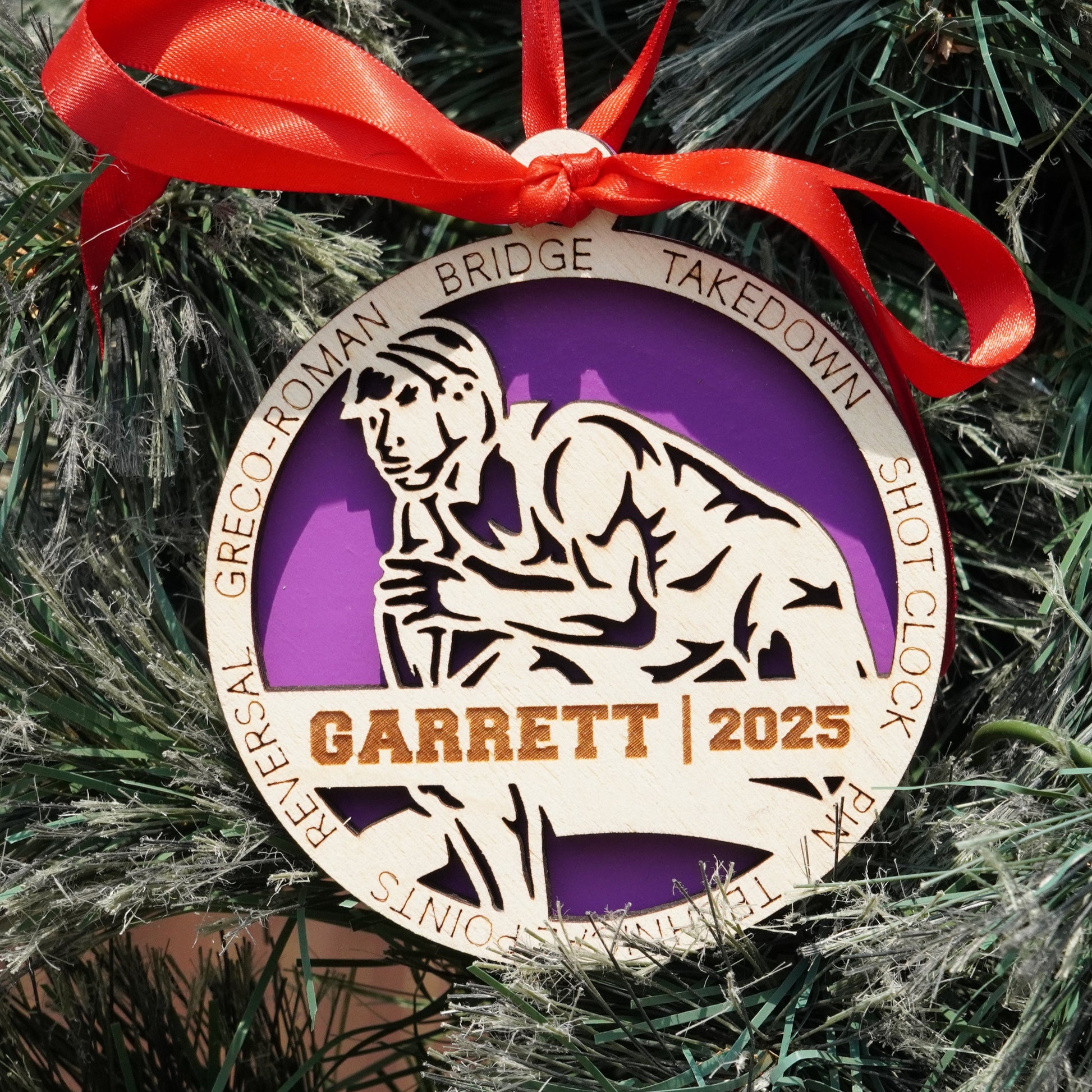 Decorative ornament with a purple circle and bear illustration, hanging on a Christmas tree. Decorative ornament with a red ribbon on a Christmas tree, featuring a wrestler, wrestling ornament, christmas gift for wrestler, wrestling ornament,