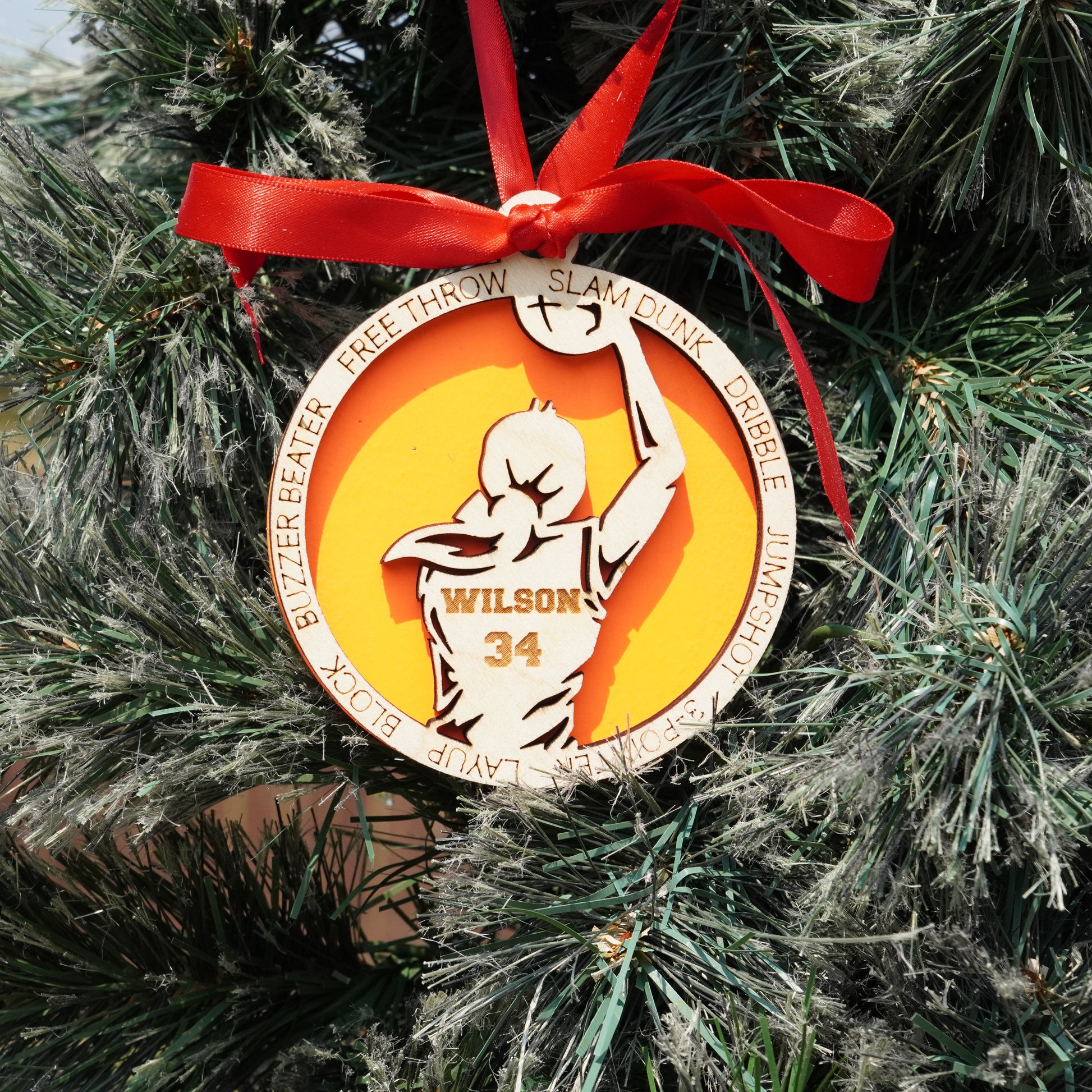Decorative basketball ornament with a red ribbon on a Christmas tree.