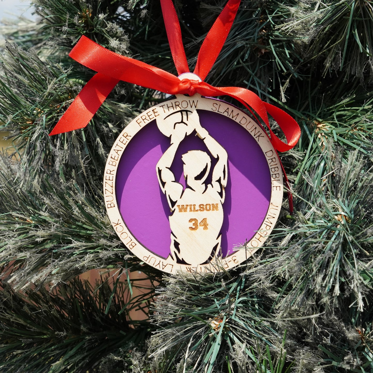 Basketball-themed ornament with a purple circle and red ribbon on a Christmas tree.