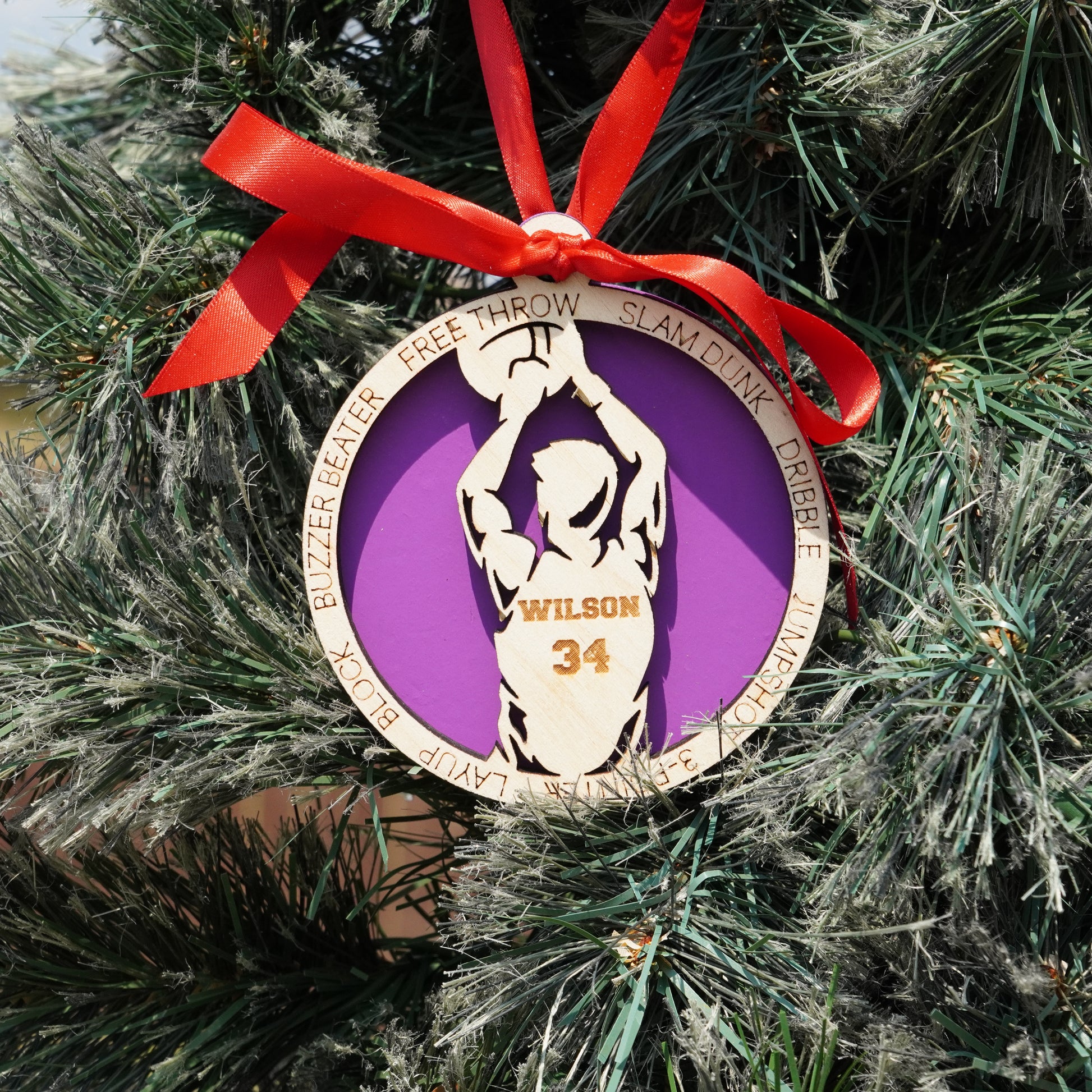 Basketball-themed ornament with a purple circle and red ribbon on a Christmas tree.