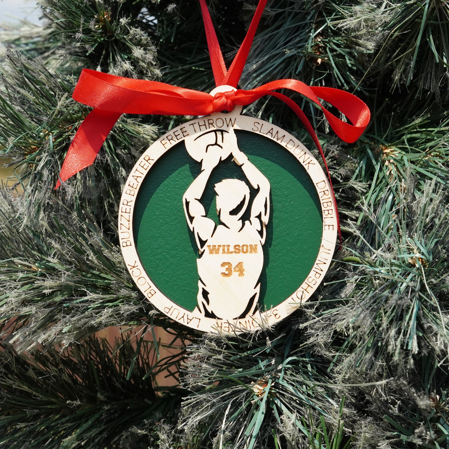 Basketball ornament with a player design and red ribbon on a Christmas tree.